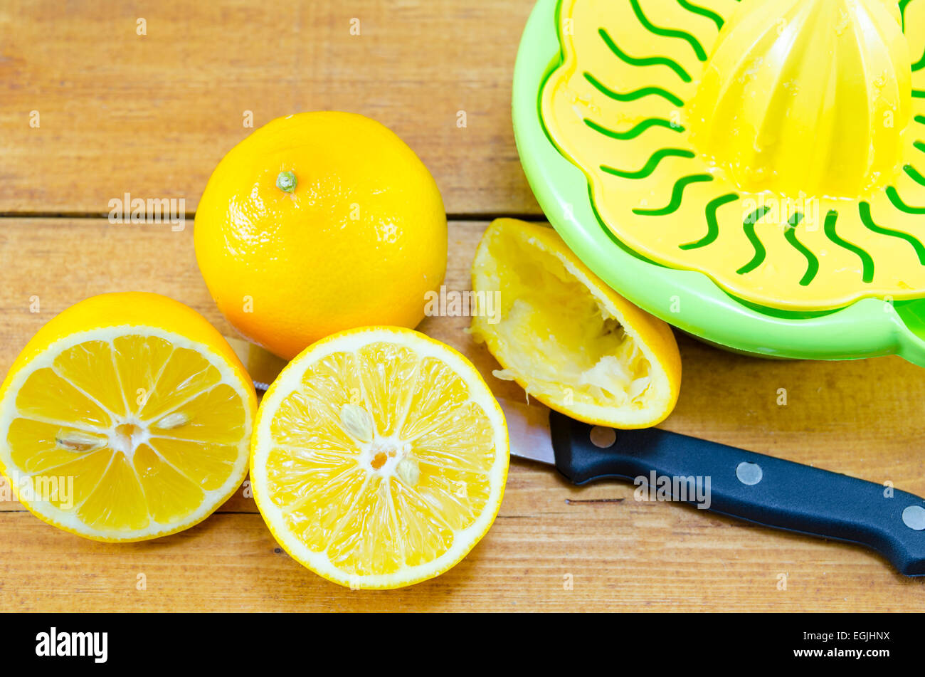 Intero e dimezzato i limoni e uno spremitore di limone su una tabella di bambù Foto Stock