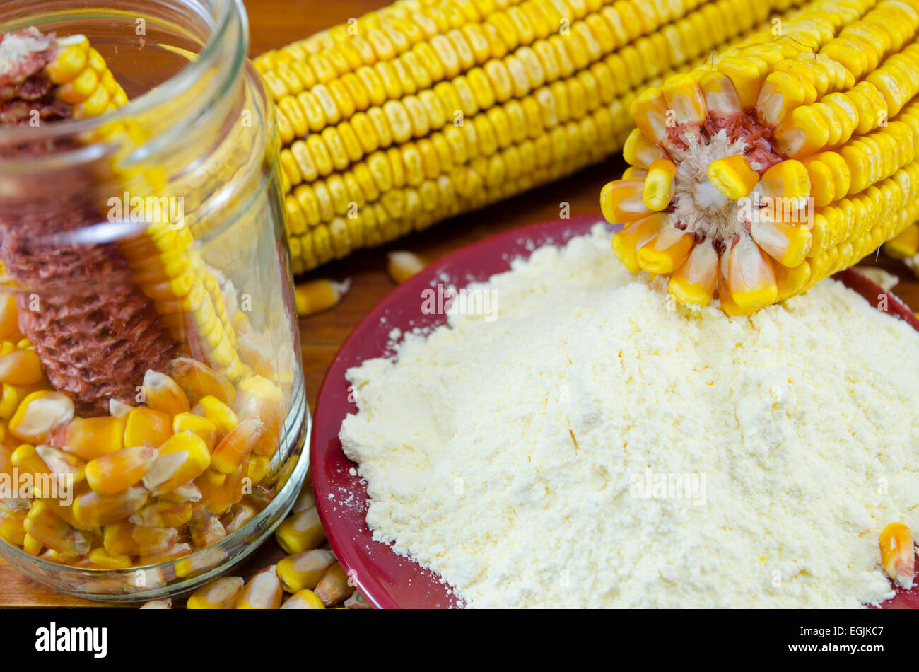 Un vaso con il mais, la farina di mais e orecchio su una tavola di legno Foto Stock
