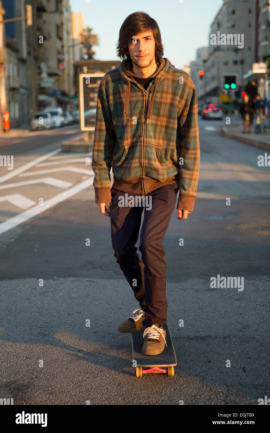 Il giovane skater cruising il centro della città alla fine della giornata Foto Stock