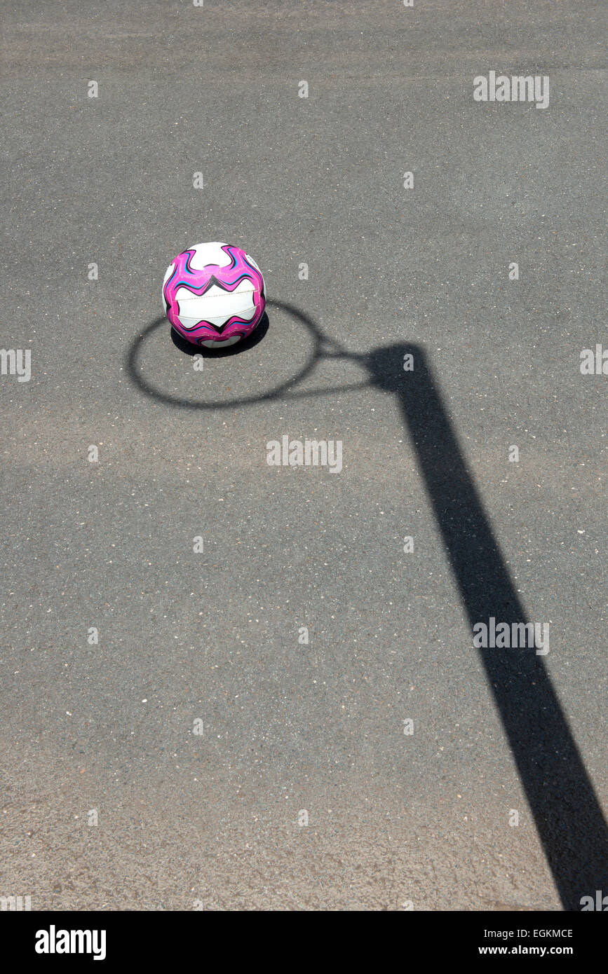 Netball in appoggio sul terreno con l'ombra del cerchio che circonda la sfera. Foto Stock