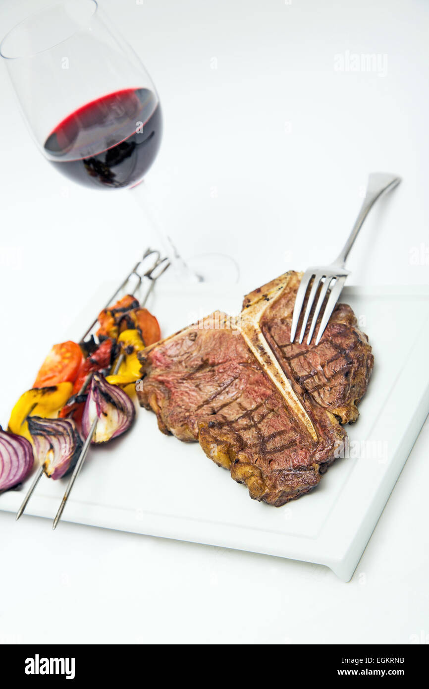 Charbroiled bistecca con vino rosso e verdure alla griglia su una piastra,isolato su bianco, formato orizzontale Foto Stock