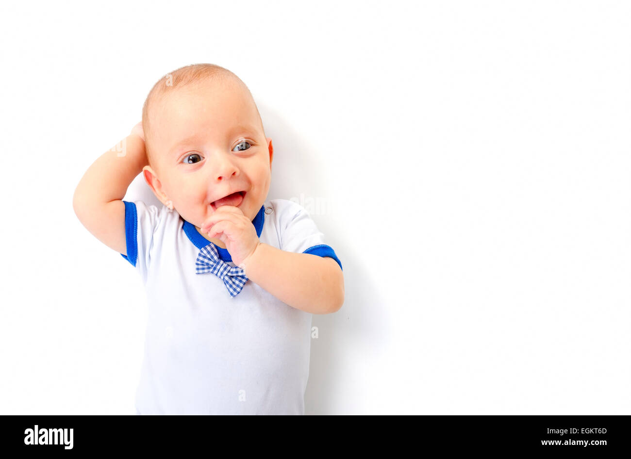 Sorridente bambino sdraiato sul pavimento bianco Foto Stock