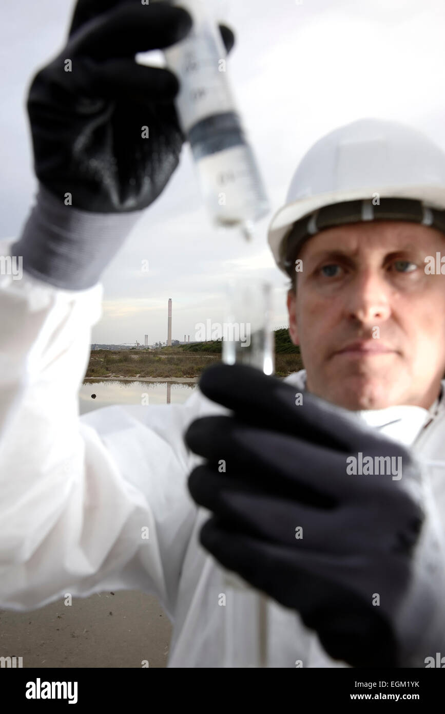 Lavoratore in una tuta protettiva esaminando inquinamento dell' acqua all'industria. Foto Stock