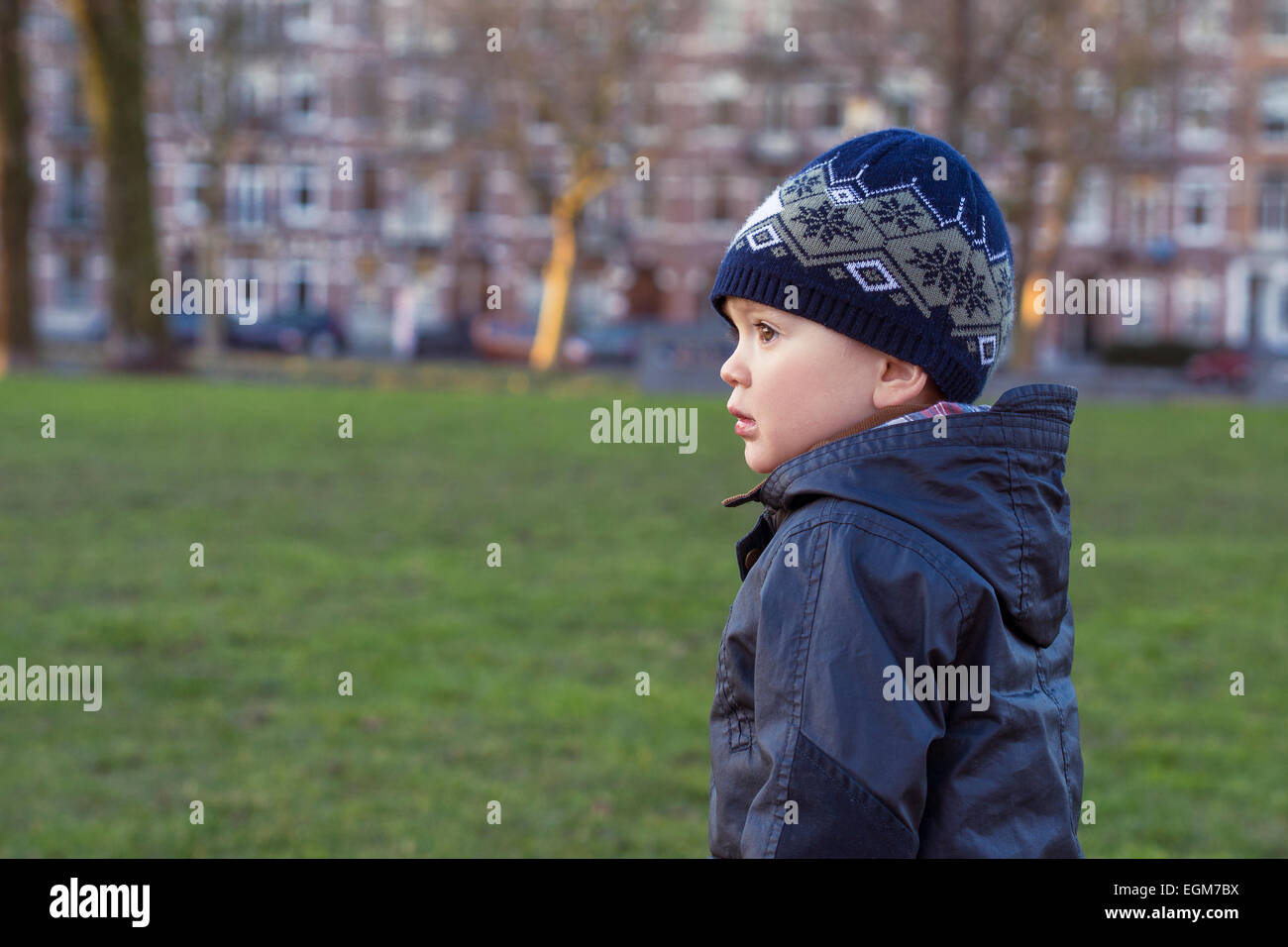 Ritratto di profilo di un piccolo ragazzo che sta al di fuori in una città europea. Foto Stock