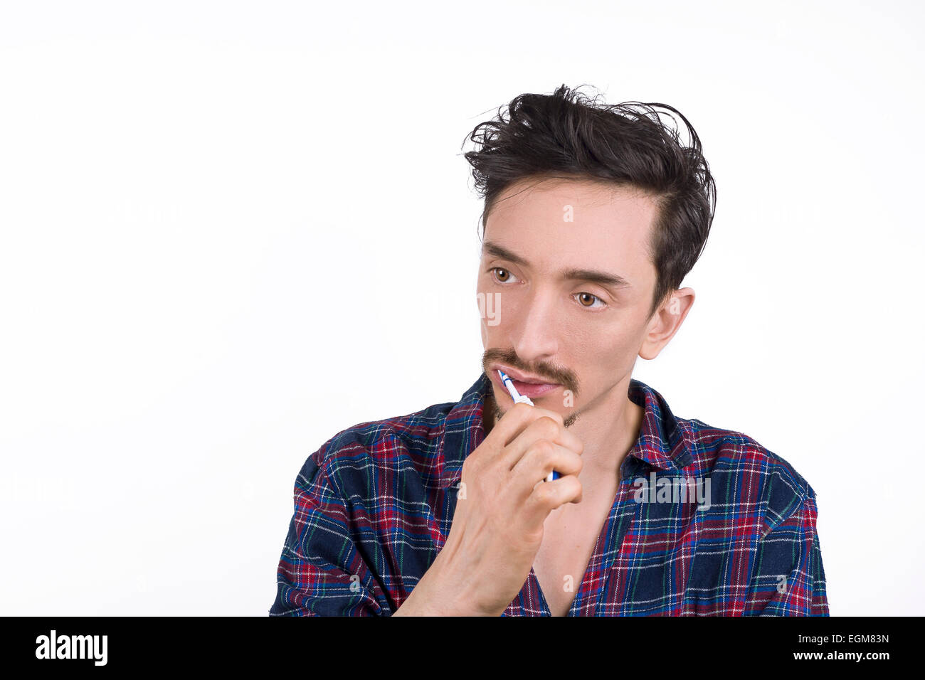 Ritratto isolata di un uomo spazzolando i suoi denti indossando pigiami Foto Stock