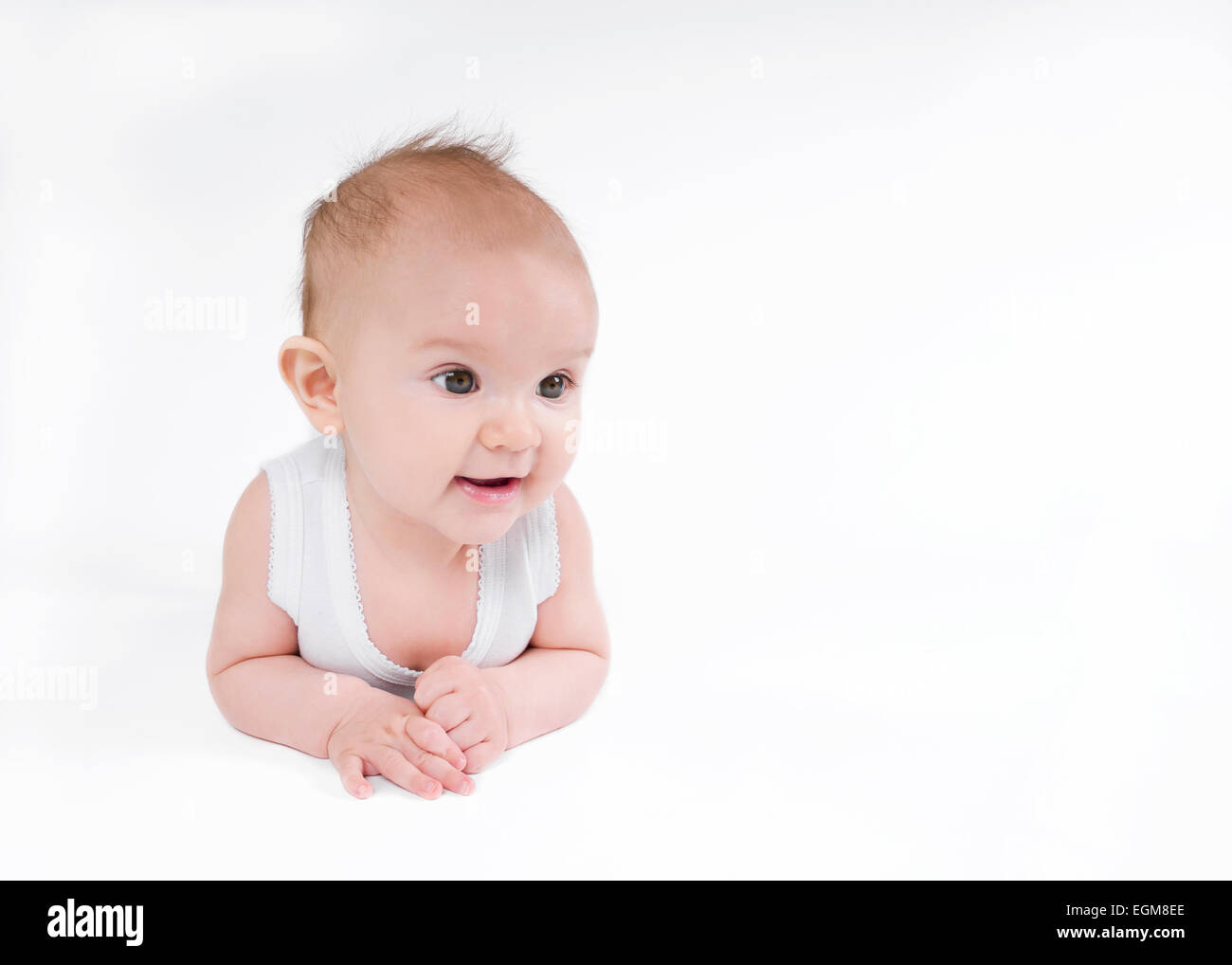 Ritratto di un simpatico baby girl posa sul ventre guardando verso l'interno Foto Stock