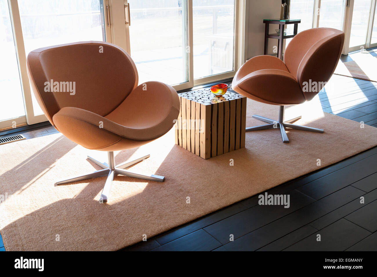 Due moderni Orange sedie girevoli sull'area Rug, pavimento in legno scuro Foto Stock
