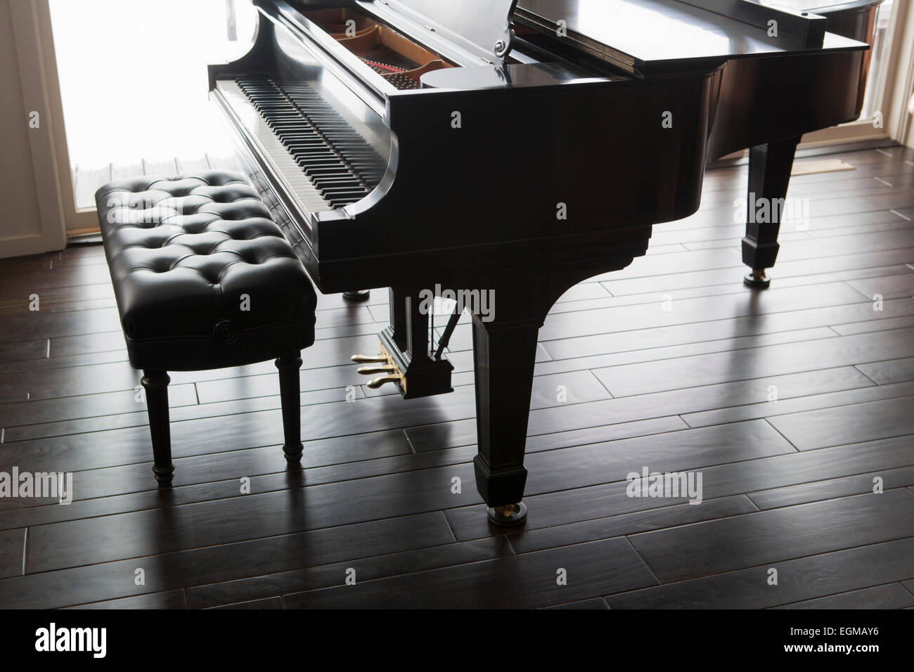 Pianoforte a coda e panca su pavimento in legno scuro Foto Stock