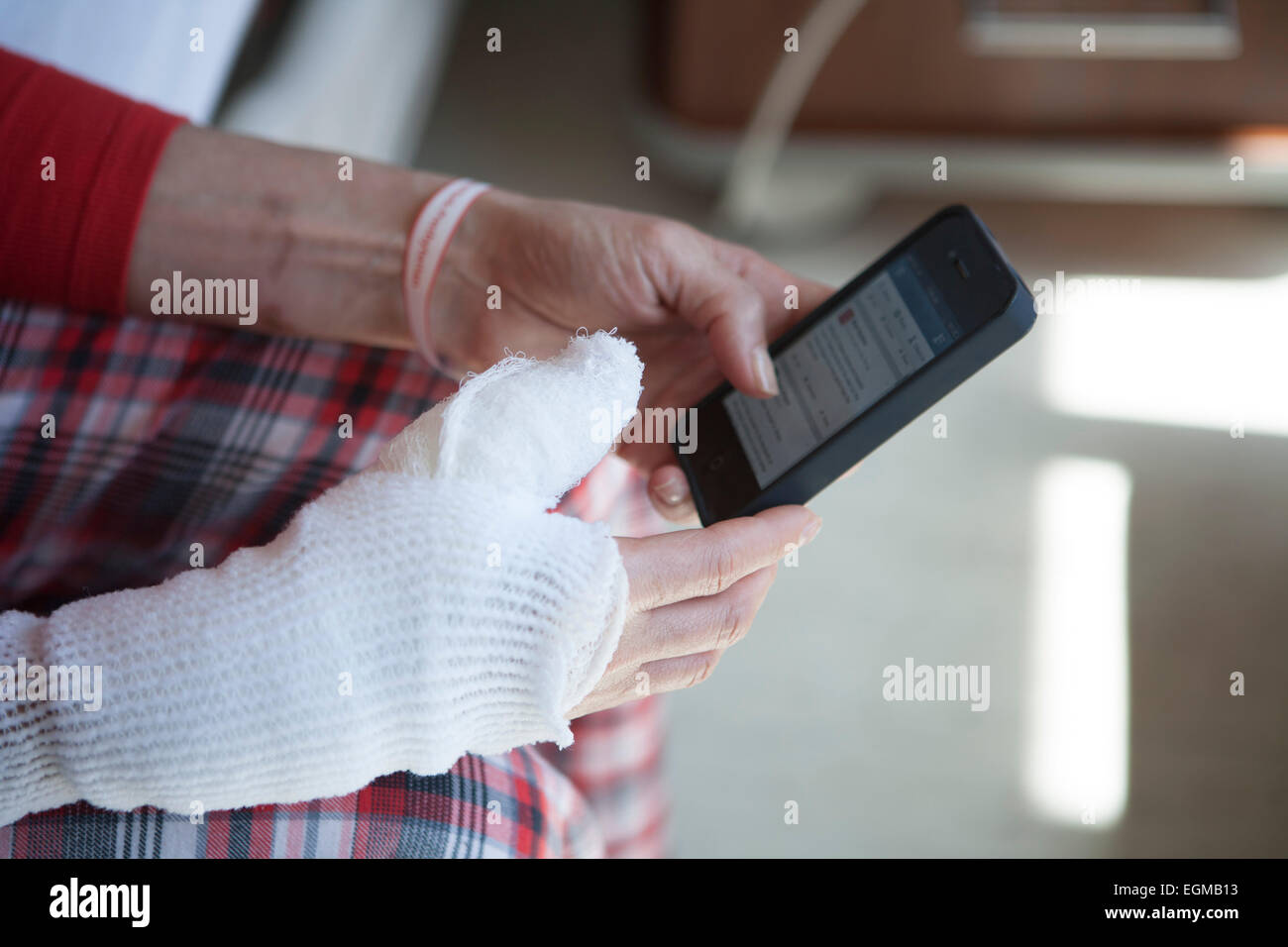 Masterizzazione femmina paziente con mano bendato e braccio utilizzando Smart Phone Foto Stock