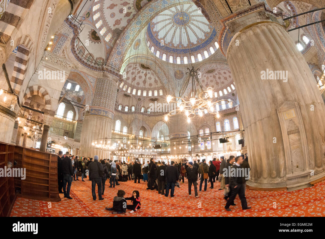 Le cupole interne e i lampadari della Moschea Sultan Ahmed Istanbul Turchia // ISTANBUL, Turchia — le cupole e le semi-cupole decorate ornamentali della Moschea Sultan Ahmed mostrano intricate calligrafie islamiche e motivi geometrici. I tradizionali lampadari ottomani (kandil) sospesi dalle cupole illuminano le famose piastrelle blu della moschea Iznik. La complessa disposizione architettonica delle cupole a cascata rappresenta il culmine del design classico della moschea ottomana. Foto Stock