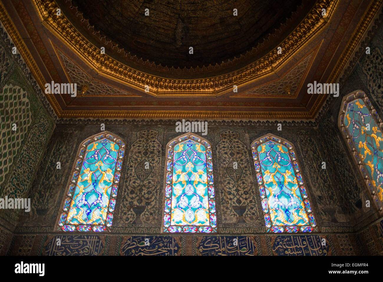 Palazzo Topkapi vetrate dell'Harem imperiale Istanbul Türkiye | ISTANBUL, Türkiye - vetrate colorate che brillano all'interno di una camera a cupola dell'Harem imperiale al Palazzo Topkapı, i loro motivi turchesi e dorati sono incastonati in pareti rivestite in piastrelle di İznik. L'Harem era il quartiere residenziale privato del sultano, e stanze come questa risalgono in gran parte alle campagne di costruzione realizzate dall'architetto Sinan alla fine del XVI secolo. Foto Stock