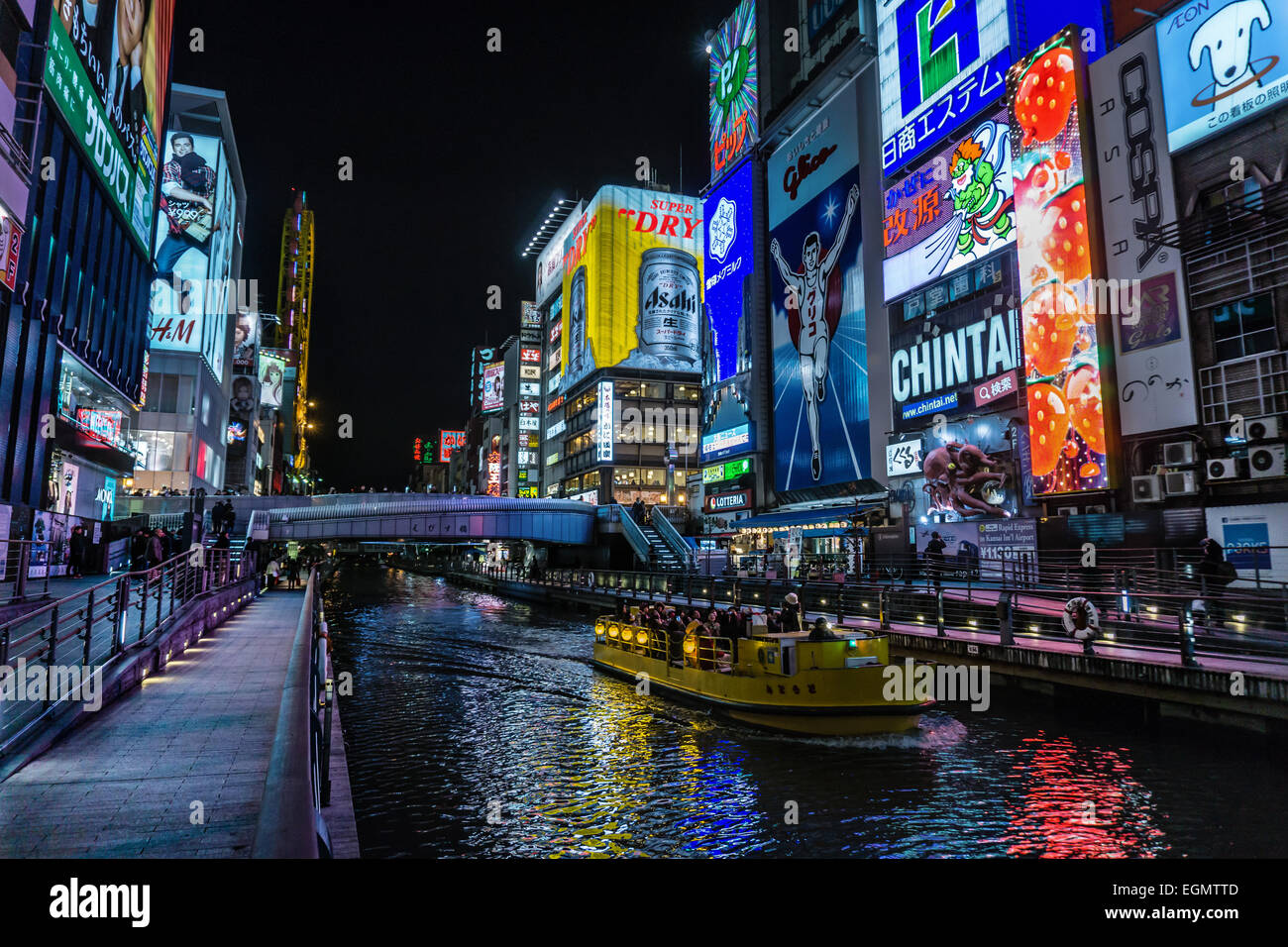 Una barca che passa lungo il fiume Dotonbori, sotto le luci al neon del centro cittadino di Osaka, Giappone Foto Stock