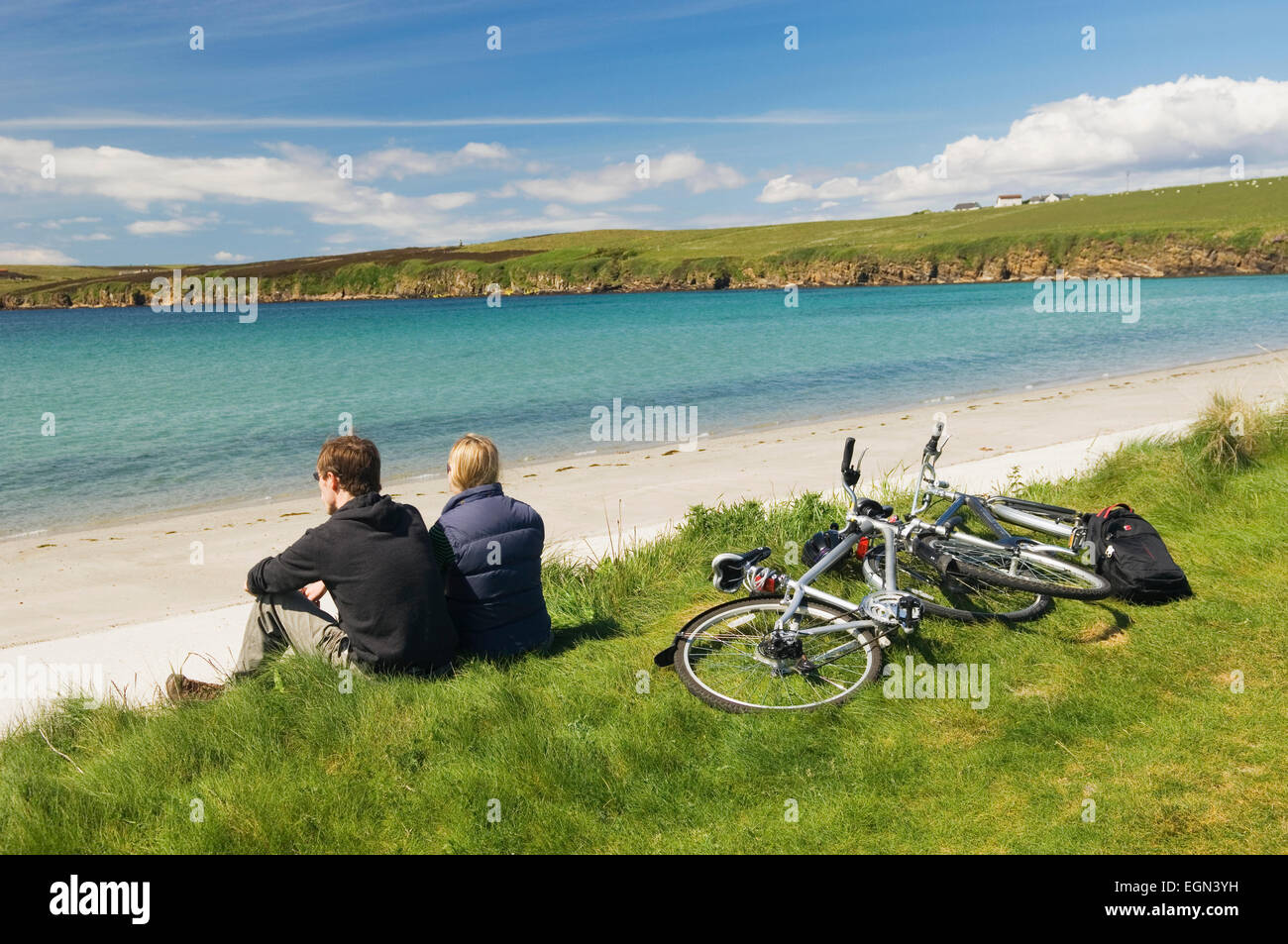 Giovane uomo e donna appoggiato accanto a loro bicicletta pedalando su South Ronaldsay, Orkney Islands, Scozia. Foto Stock