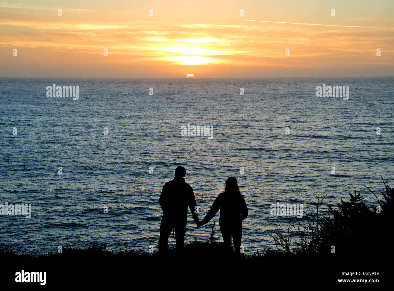 L uomo e la donna si stringono la mano durante la visione di un tramonto a Mendocino California USA Foto Stock