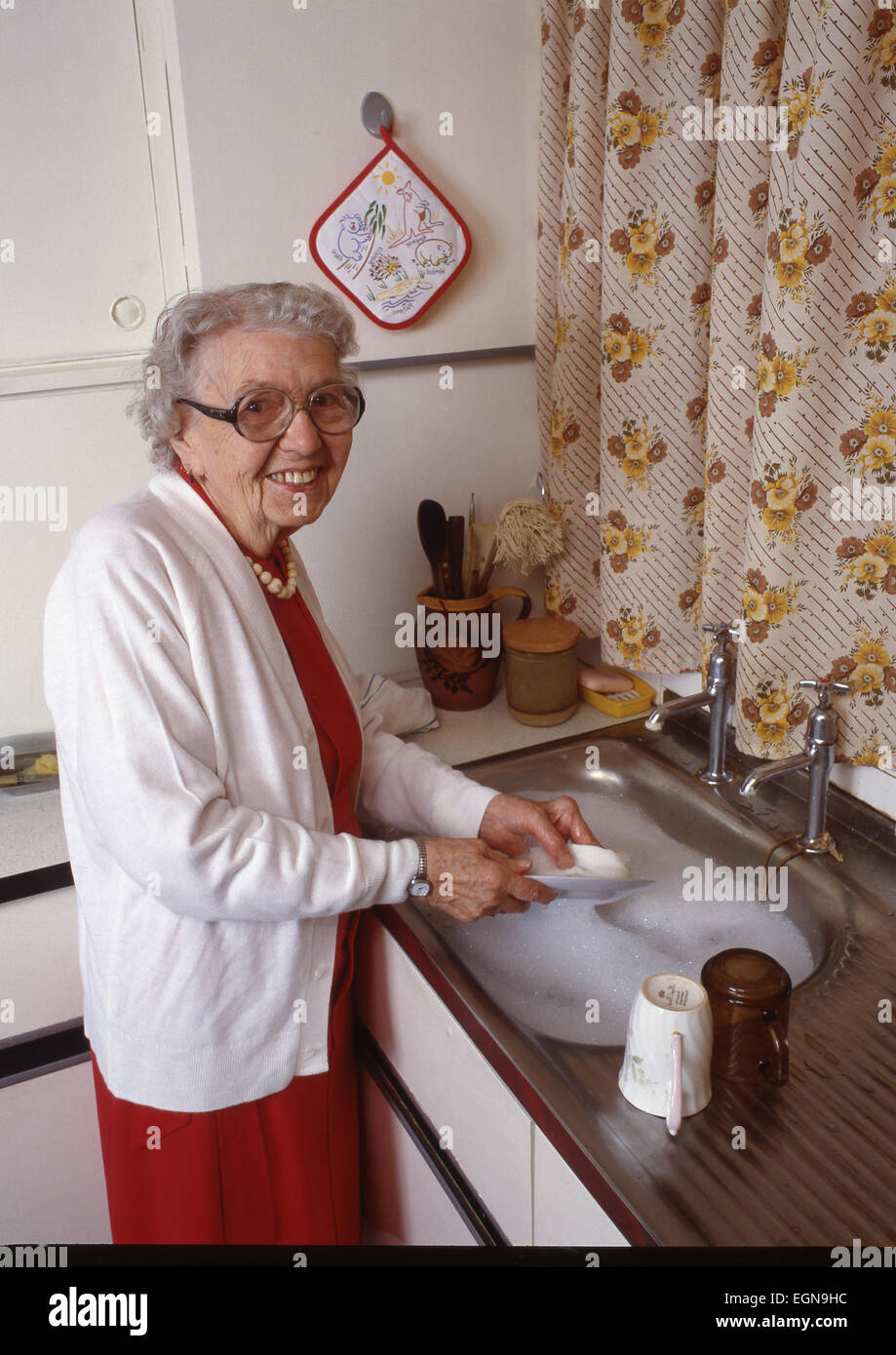 Old Lady lavaggio fino al lavello in cucina Foto Stock