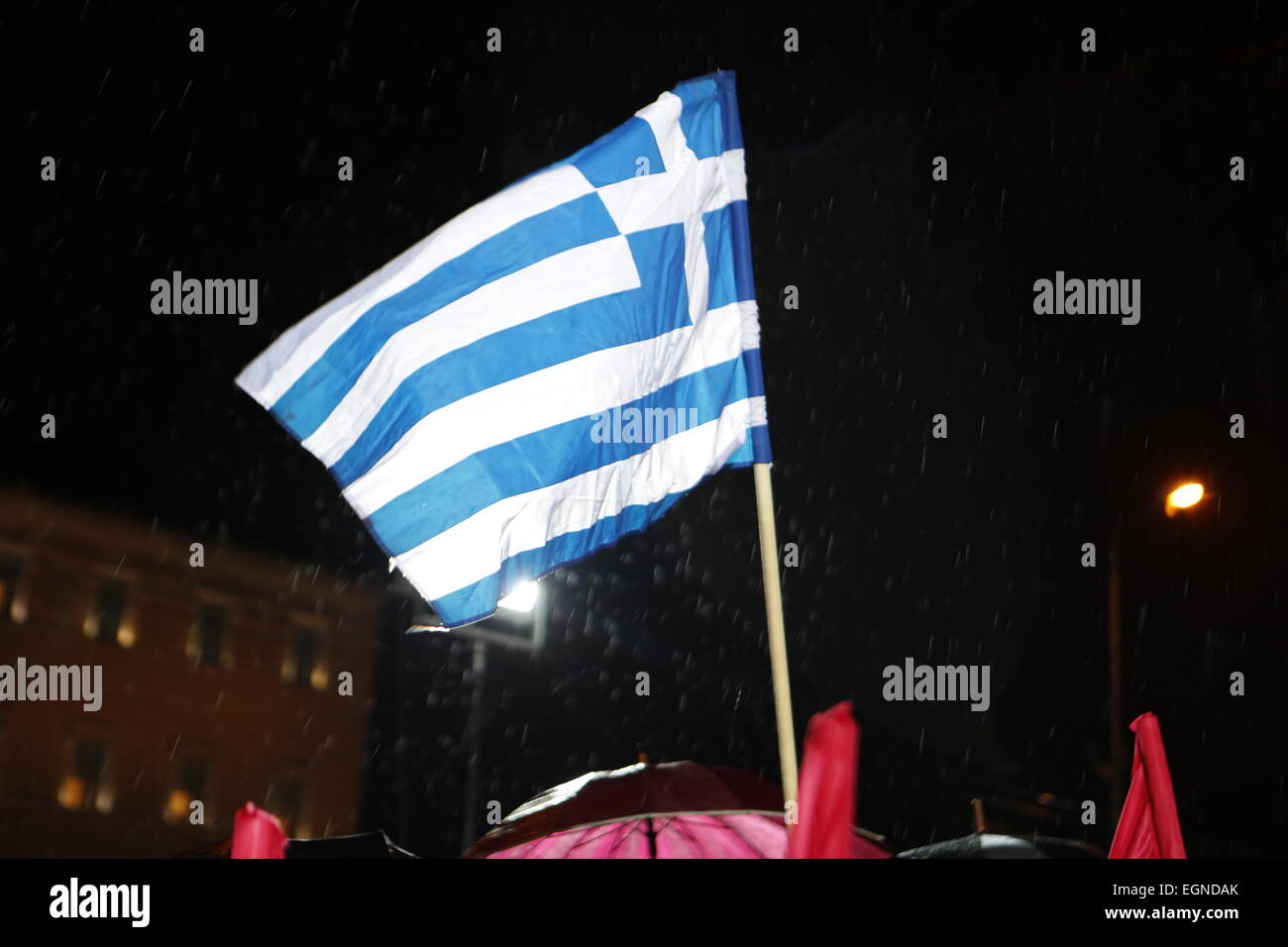Atene, Grecia. Il 27 febbraio, 2015. Una bandiera greca vola durante la protesta di migliaia di greci seguita la chiamata del Partito comunista di Grecia (KKE) nonostante la pioggia pesante, per protestare contro la politica del governo greco, che continuano a seguire le politiche di austerità come richiesto dall'Eurogruppo, nonostante le diverse promesse elettorali. Credito: Michael Debets/Alamy Live News Foto Stock