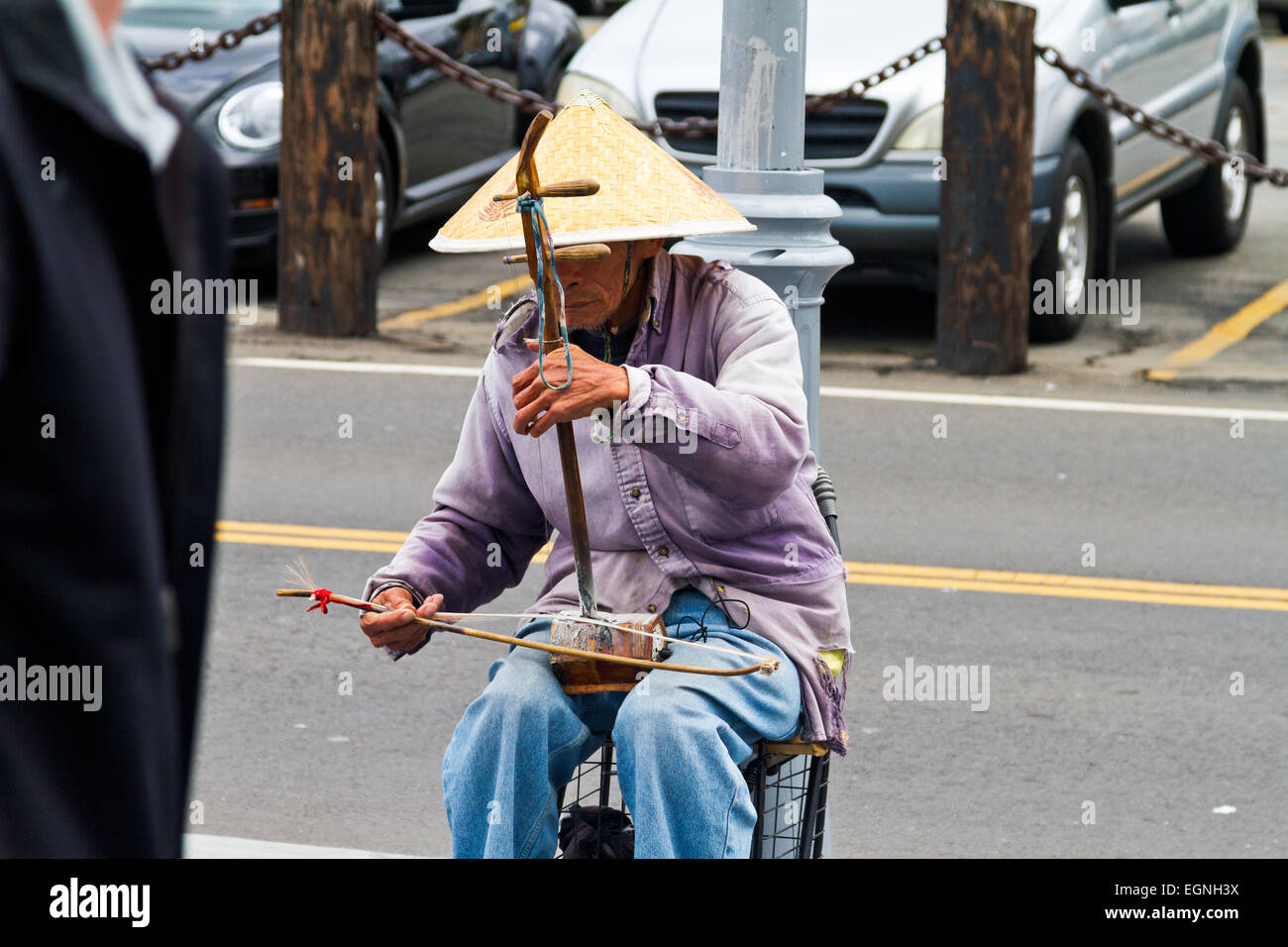Un anziano uomo cinese indossando un cappello tradizionale e la riproduzione di uno strumento tradizionale sulla strada a San Francisco. Foto Stock