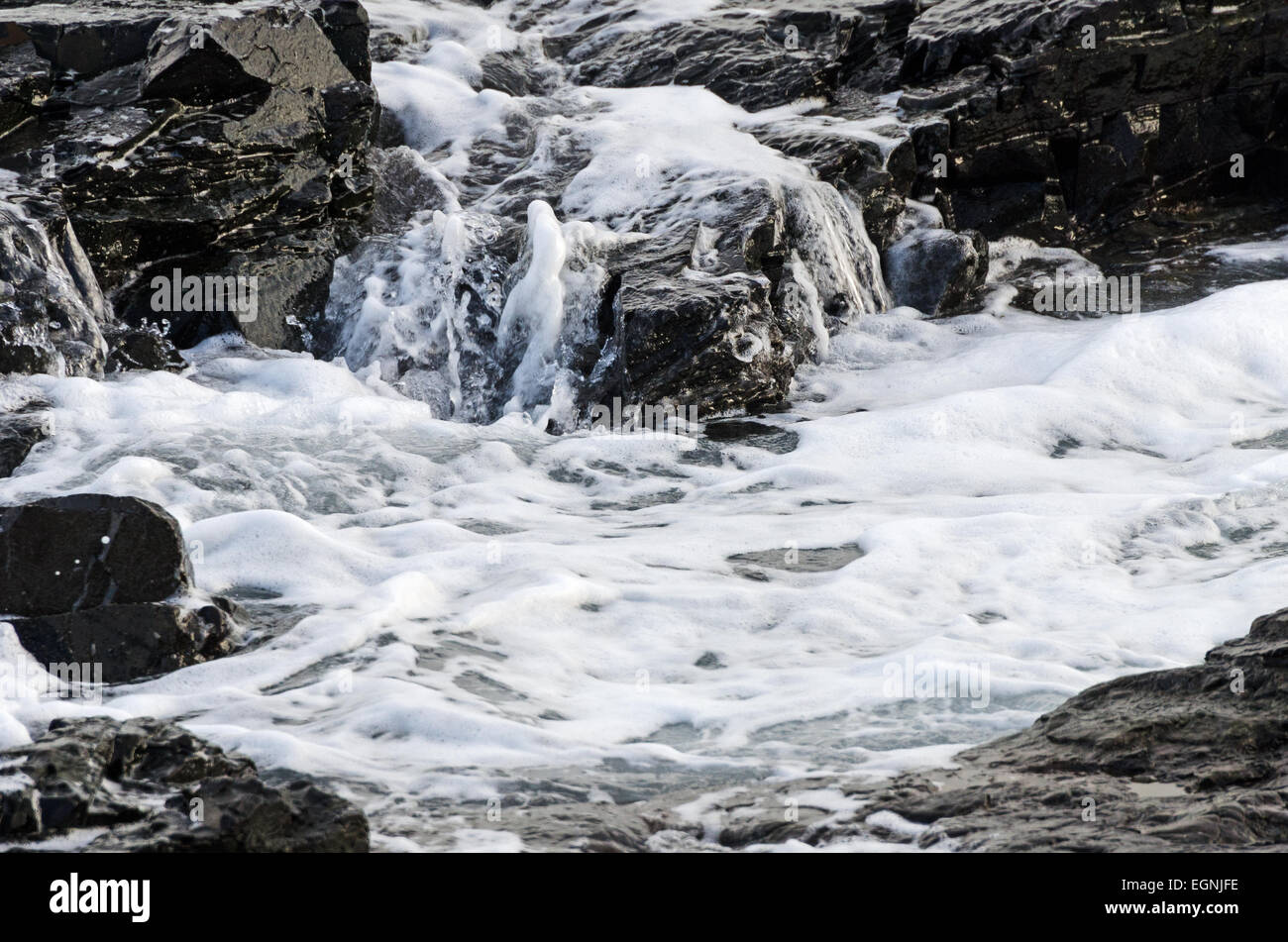 La schiuma delle onde come essi rush su icy cenge, Bar Harbor, Maine Foto Stock