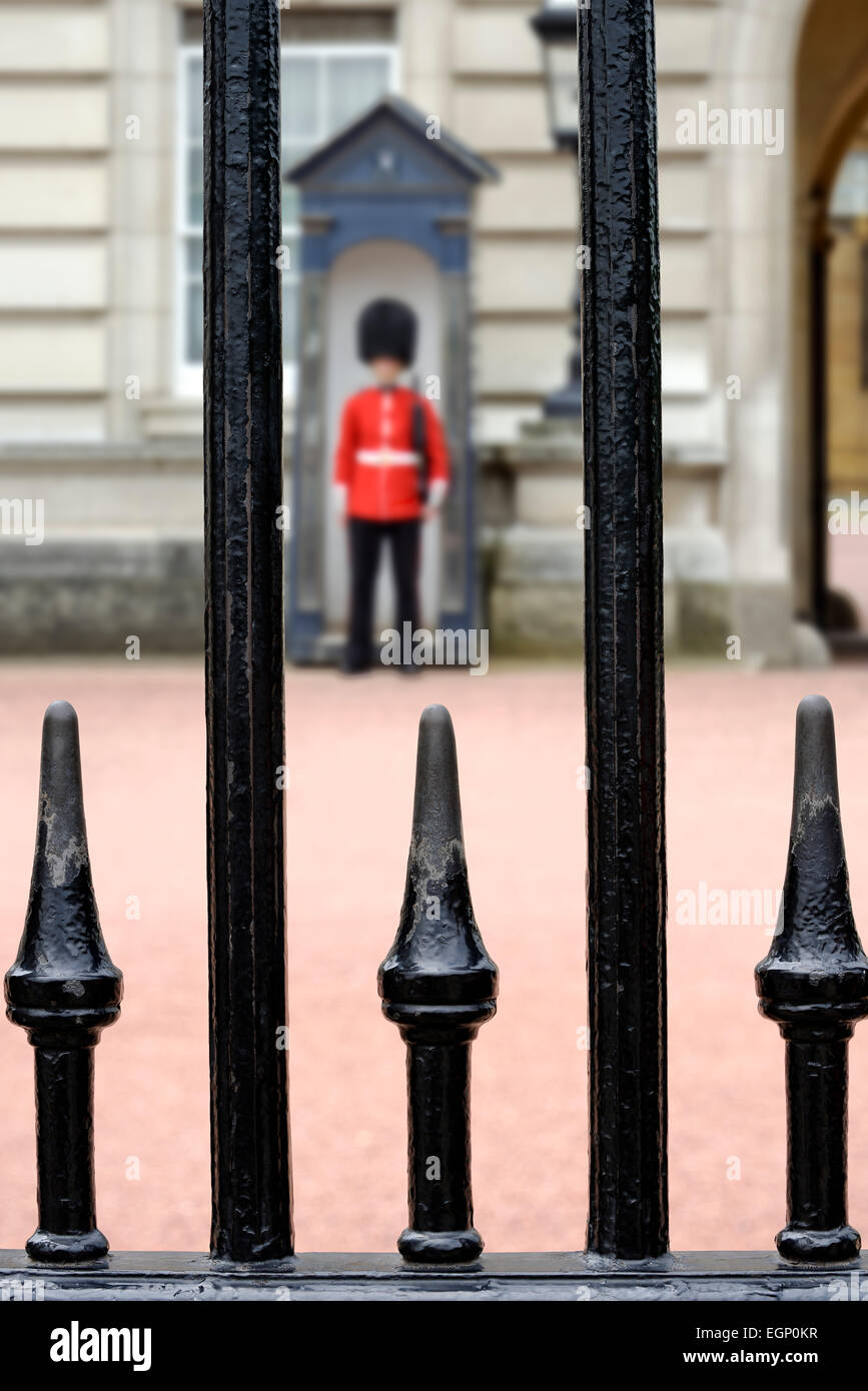 Guardsman fuori Buckingham Palace, visto attraverso le ringhiere. Londra, Inghilterra, Regno Unito. Foto Stock