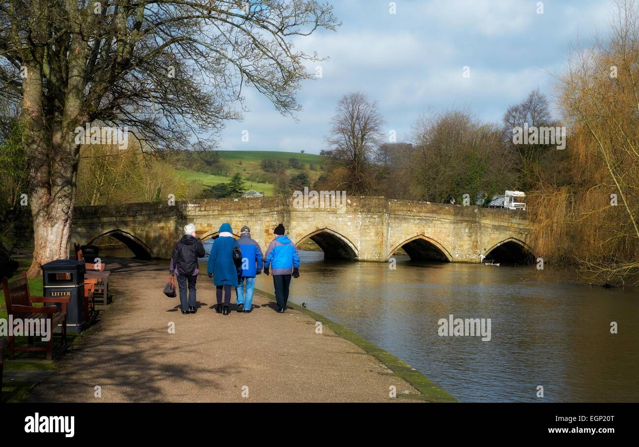 Anziani senior gente camminare lungo il fiume Wye in bakewell con il XIII secolo ponte in background Derbyshire Inghilterra Foto Stock