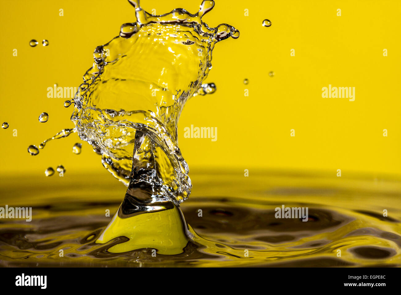 Acqua goccia collisioni con uno sfondo giallo Foto Stock