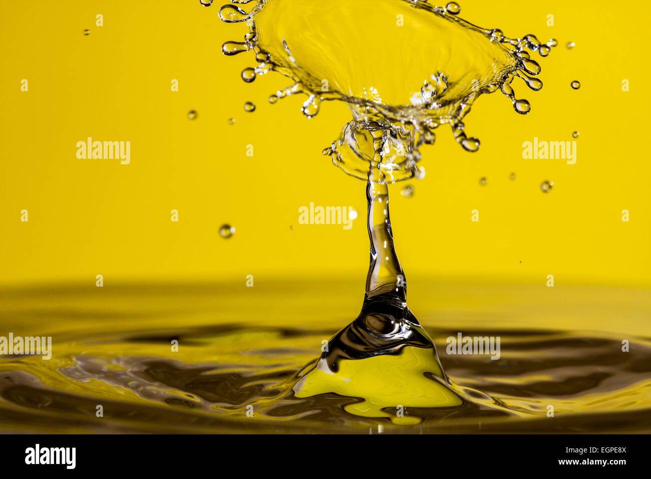 Acqua goccia collisioni con uno sfondo giallo Foto Stock
