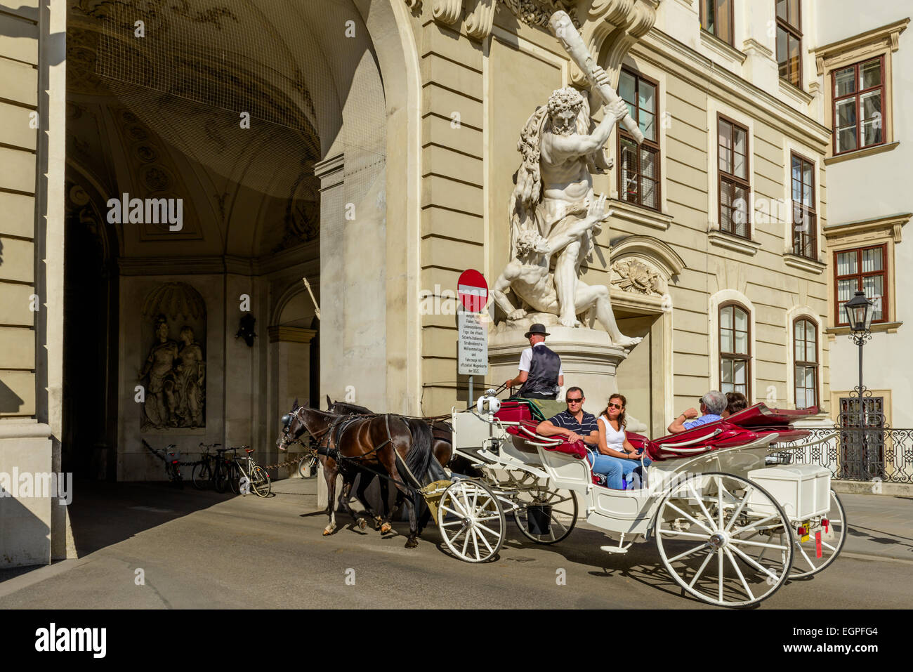 Carrozza a cavallo con i turisti a cavallo attraverso un passaggio nel Palazzo di Hofburg di Vienna, Austria Foto Stock