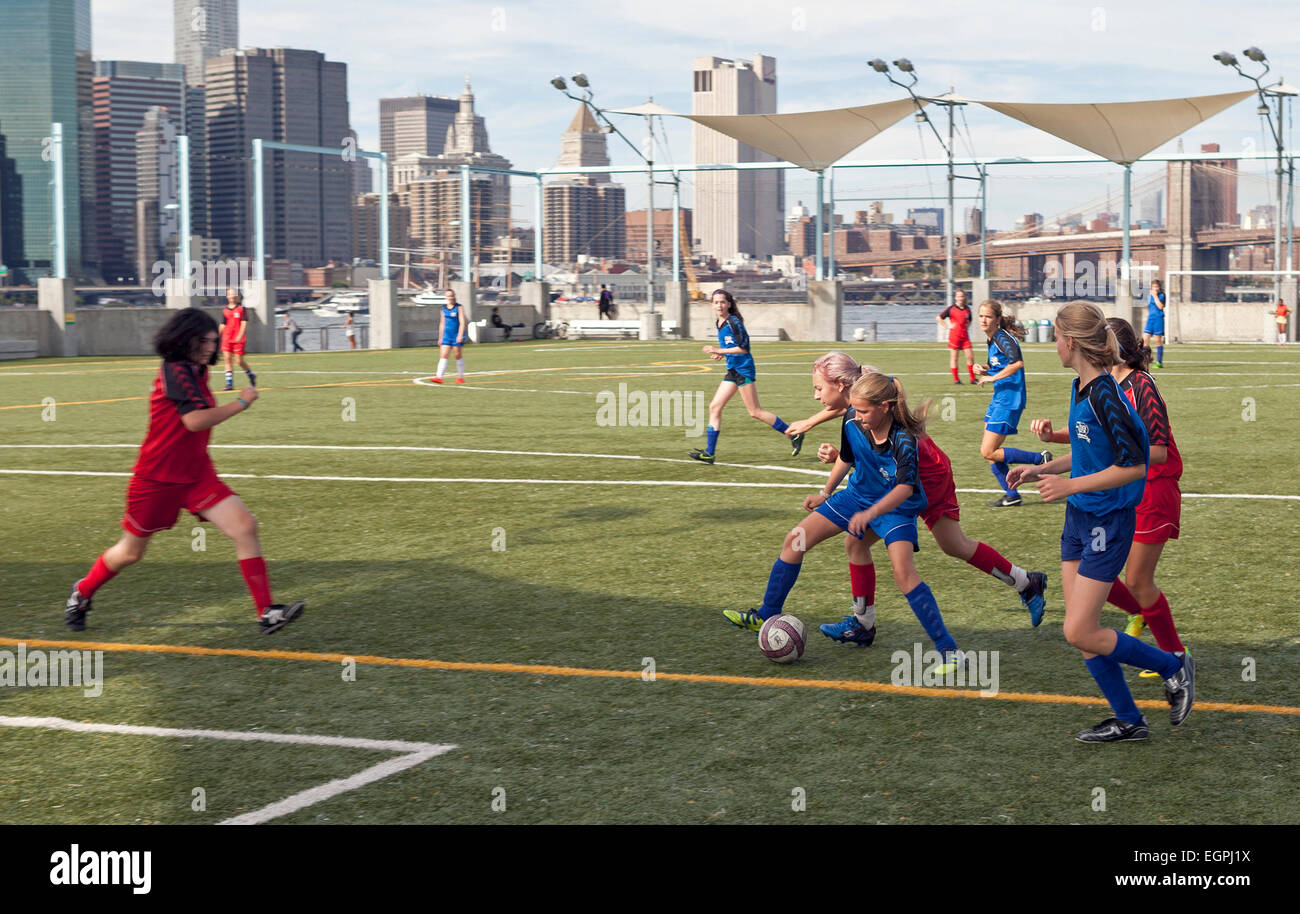 Le ragazze giocano a calcio nei campi di calcio del Brooklyn Bridge Park a New York City. Foto Stock
