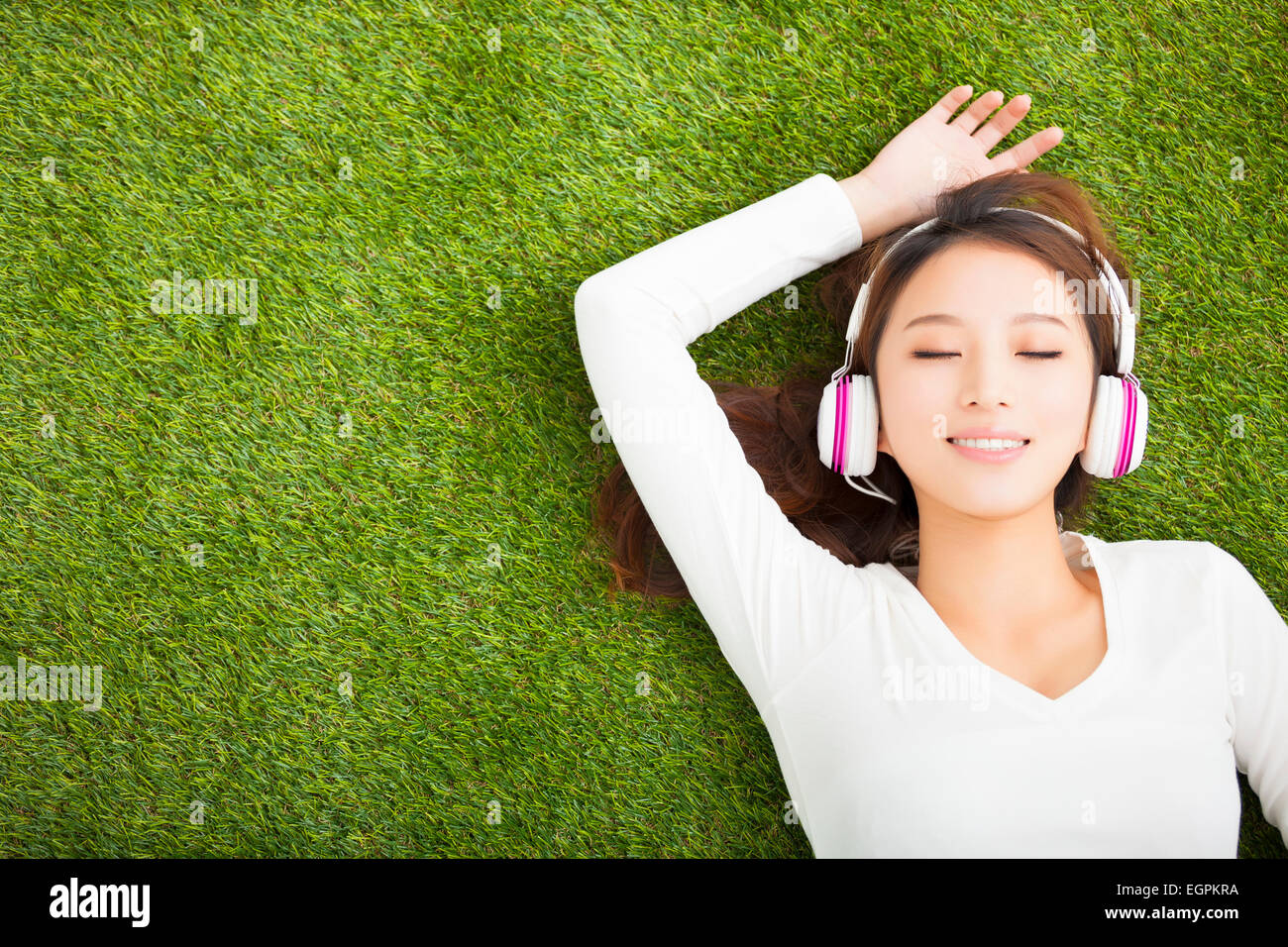 Donna rilassati ascoltando la musica con le cuffie sdraiati sull'erba Foto Stock
