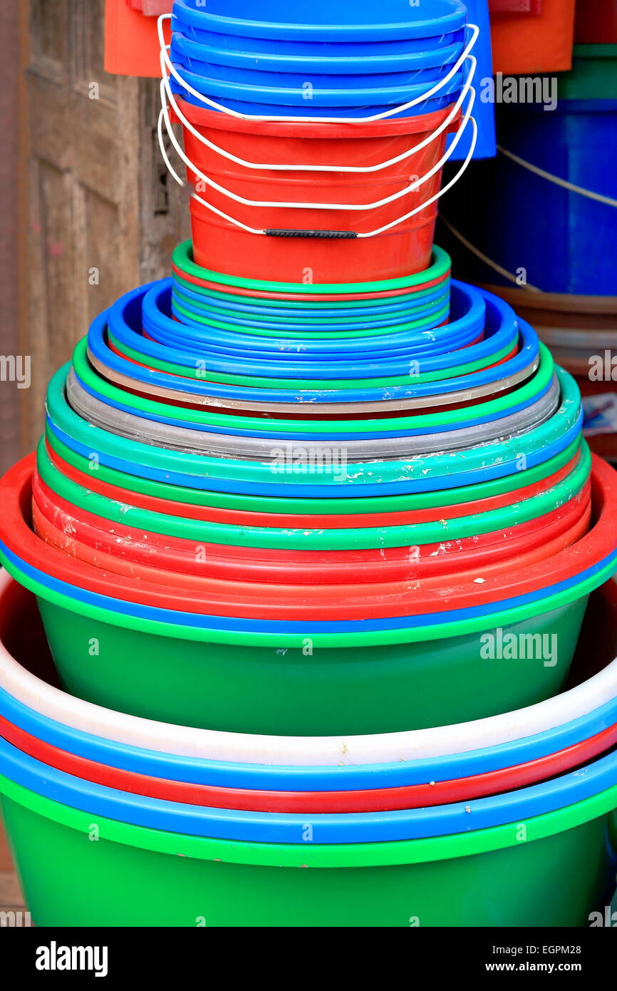 Pila di colorista secchi di plastica e le benne serie in vendita presso l'entrata di un negozio in una strada della città vecchia area-Panauti-Nepal Foto Stock