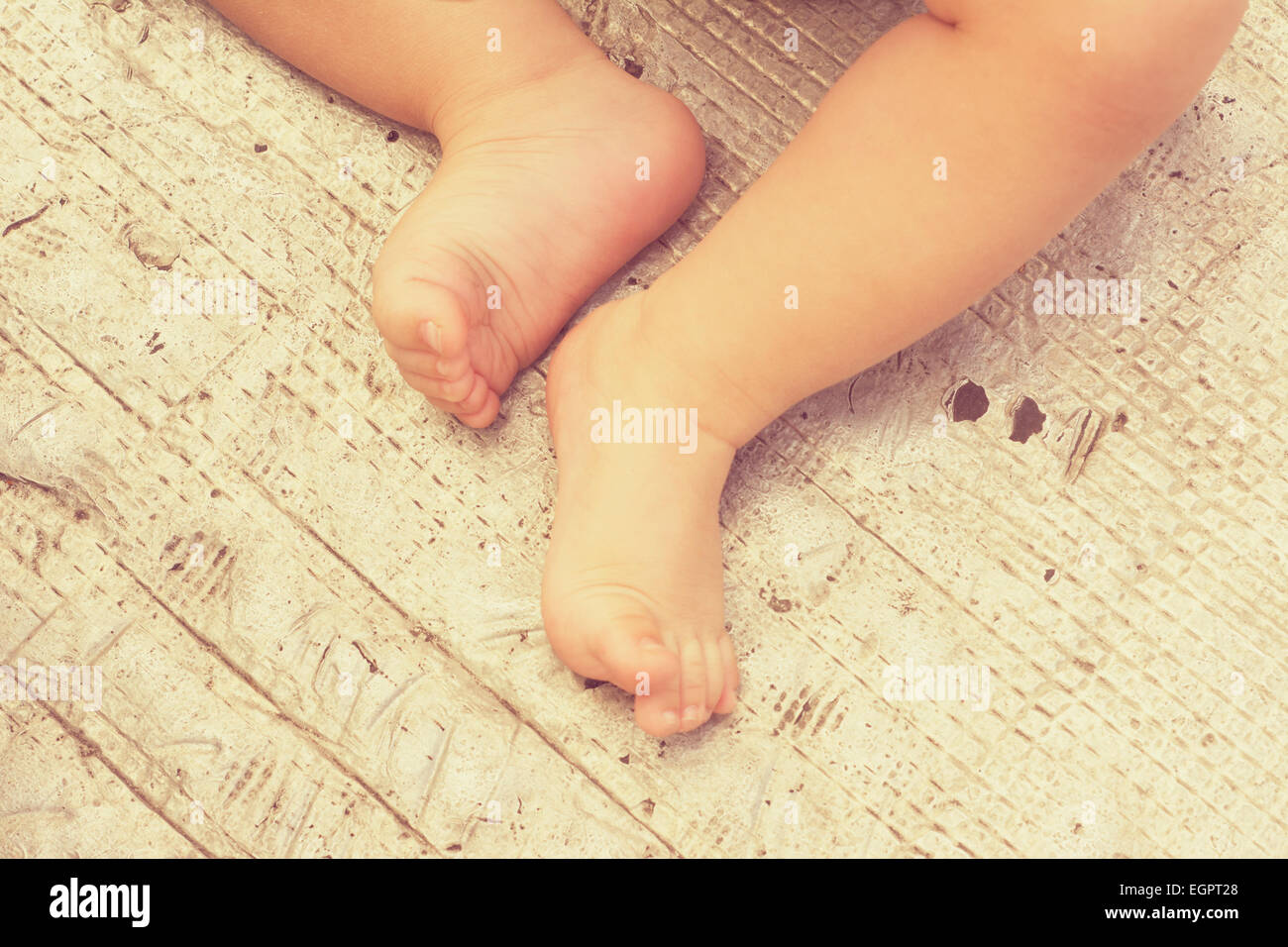 Piedi del bambino seduto sulla texture in metallo Foto Stock