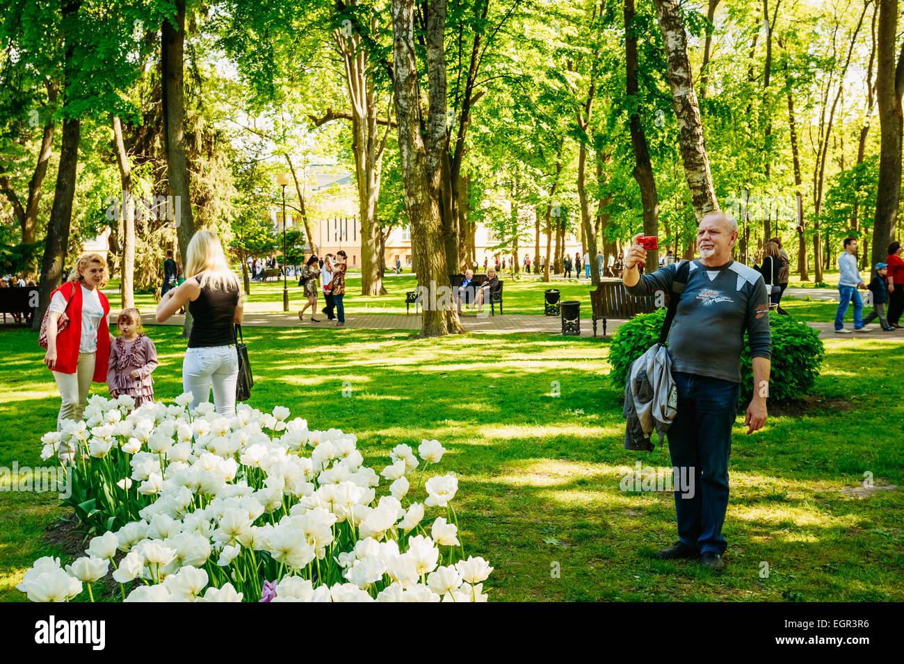 GOMEL, Bielorussia - 9 Maggio 2014: le persone non identificate sono fotografati su uno sfondo di fiori di primavera nel parco della città. Foto Stock