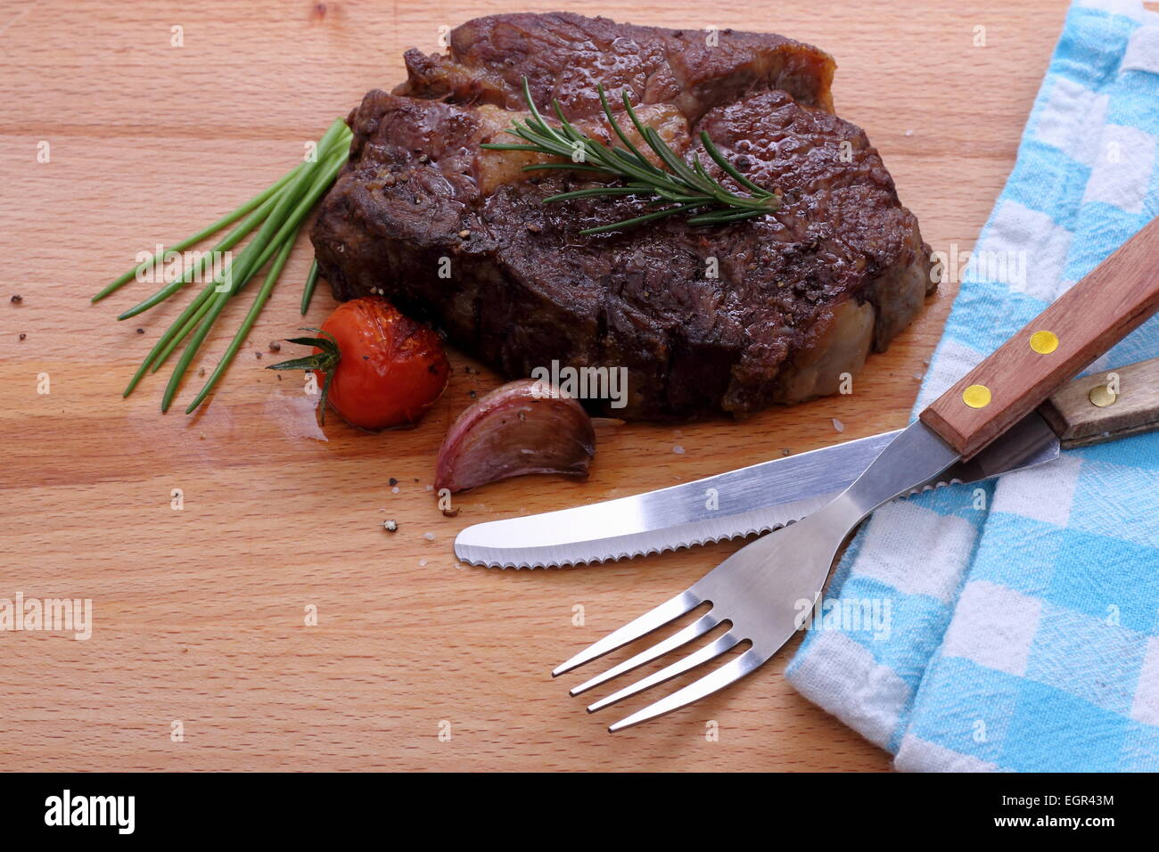 Costata di manzo, pomodori ciliegini, aglio, erbe su sfondo di legno Foto Stock