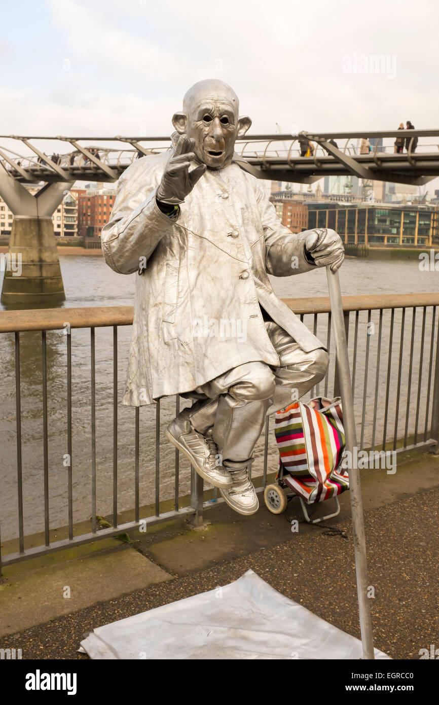 D'argento metallizzato dipinto statua umana street artista e performer su Londra Southbank nella parte anteriore del Millennium Bridge Foto Stock