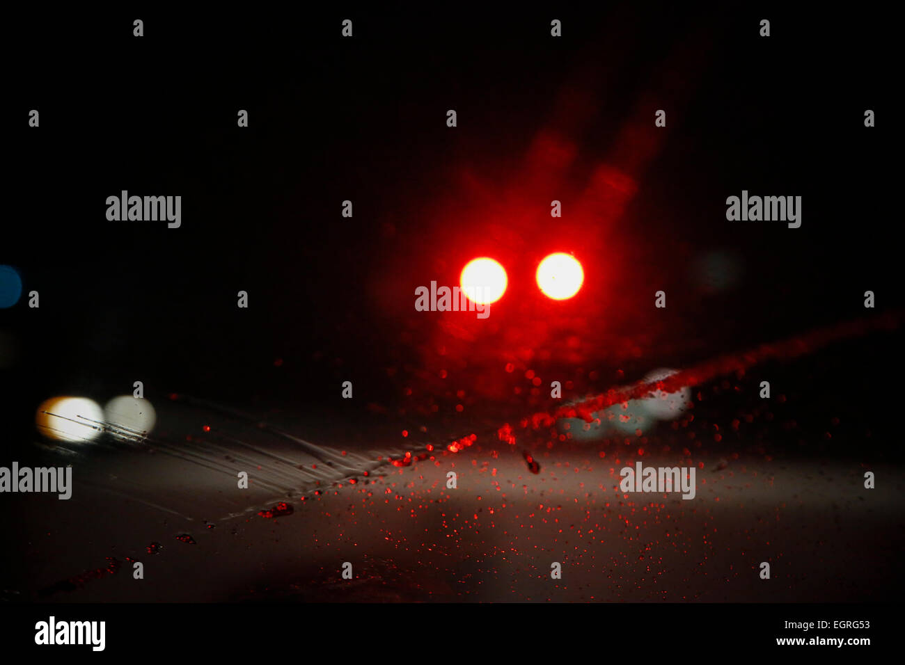 Fari anteriori su un gelido freddo, notte nevosa sono sfocate presso il tergicristallo si muove attraverso il parabrezza di un'auto. dark pericoloso Foto Stock