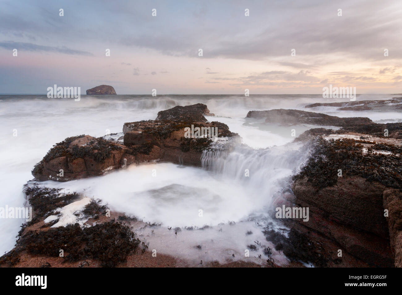 Una grande onda provoca un pool di marea a riempire Seacliff Beach. Foto Stock