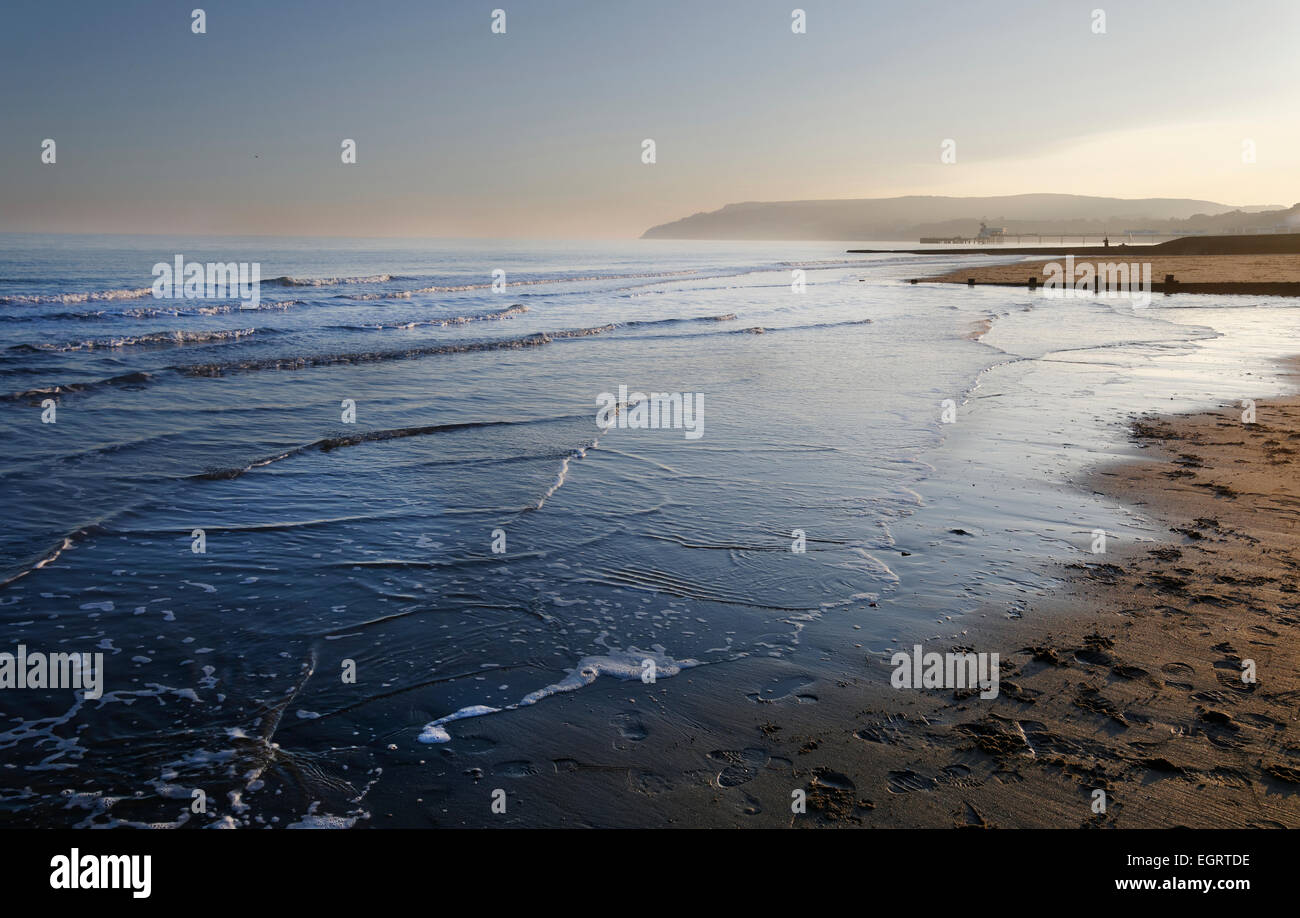 La spia luminosa si illumina Sandown Bay, Isle of Wight, con il dolce mare lambiscono la riva. Foto Stock