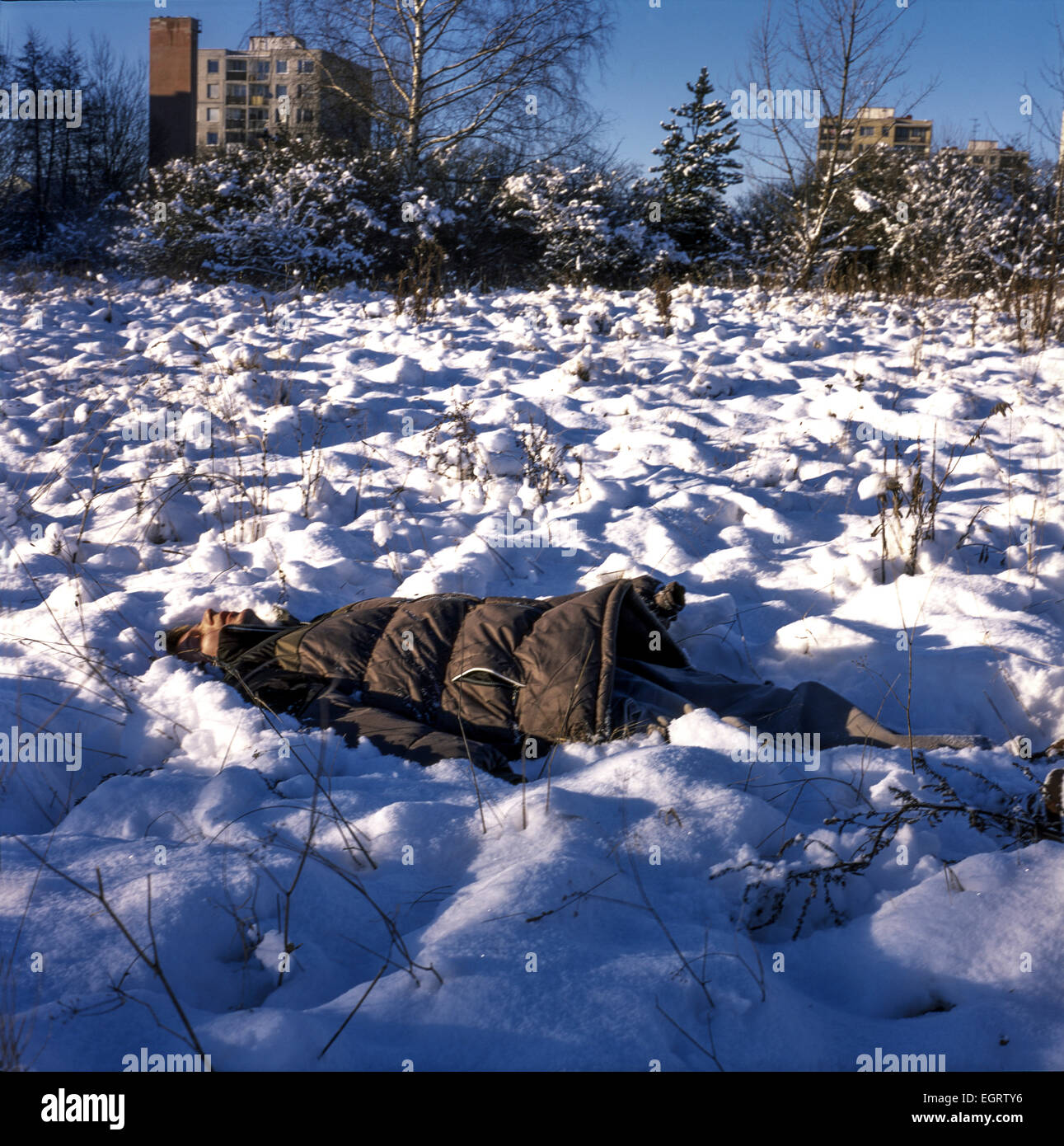 Donna sdraiata nella neve, ambientazione urbana innevata in inverno Foto Stock