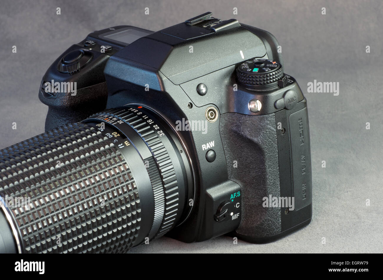 Fotocamera reflex digitale e la lente closeup contro uno sfondo grigio Foto Stock