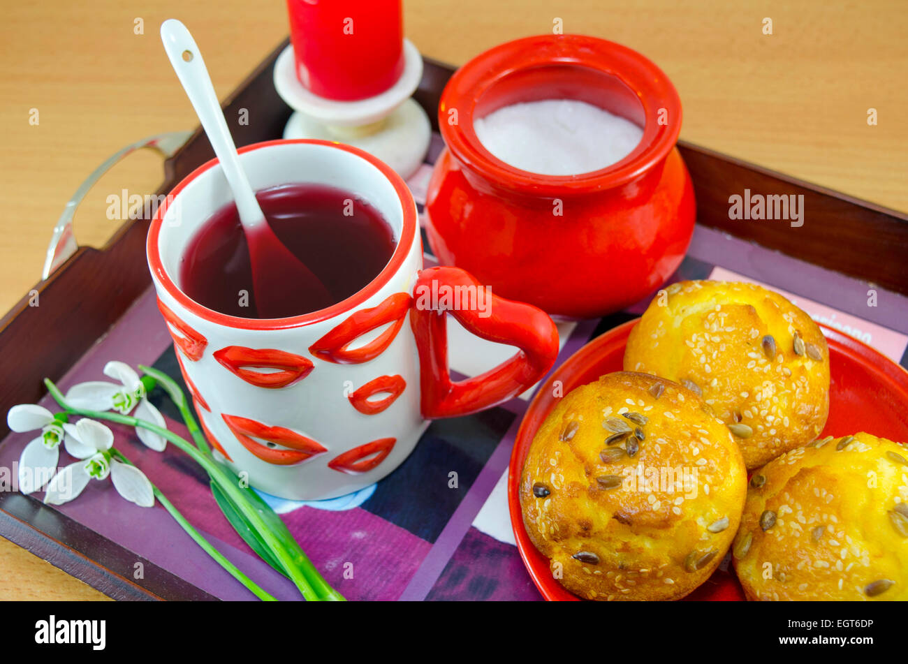 Il pane di mais con sesamo, team in un labbro modellato mug, zucchero e bucaneve su un vassoio, facendo una romantica colazione a letto Foto Stock