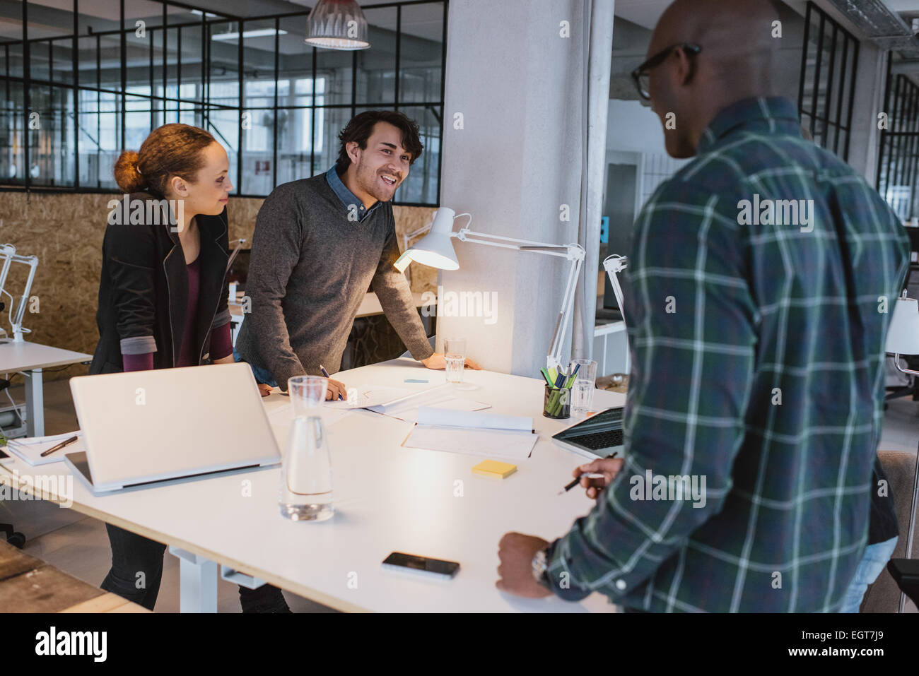 Business di successo di colleghi in piedi insieme ad una riunione. Multirazziale team creative discutendo di lavorare in posizione eretta. Foto Stock
