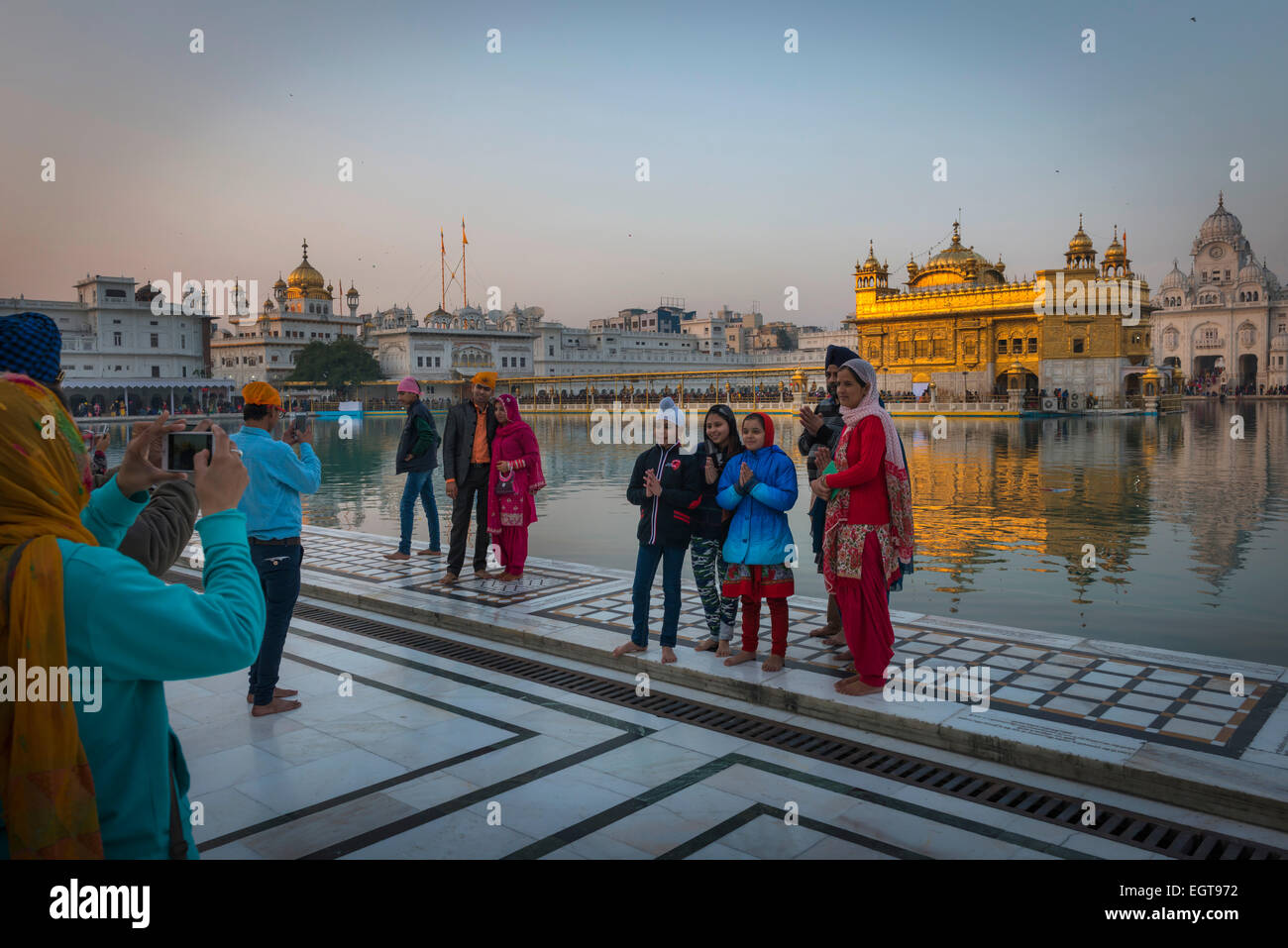 Una famiglia Sikh si riuniscono per una fotografia di fronte al Tempio d'oro, Amritsar al crepuscolo. Foto Stock