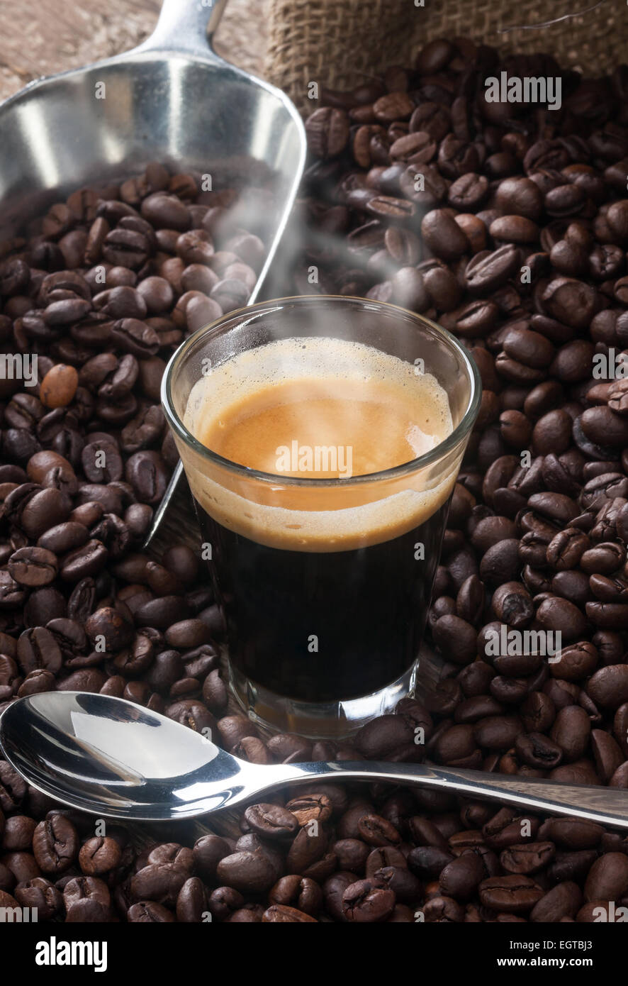 Caffè espresso in tazza di vetro con i chicchi di caffè sul tavolo di legno. Foto Stock