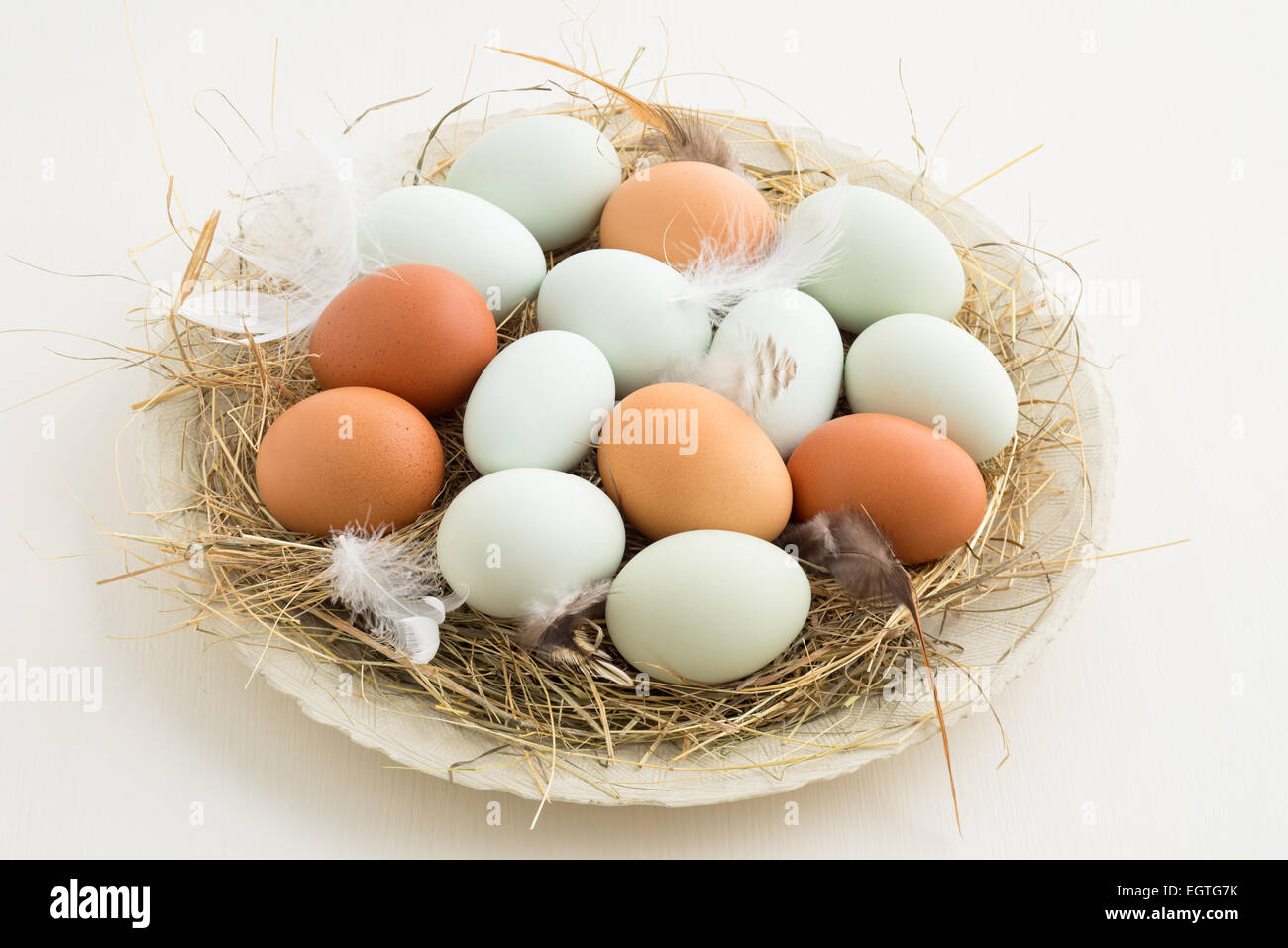 Fresca luce verde uova di Pasqua egger pollo e rosolare le uova in un nido di paglia su una piastra Foto Stock