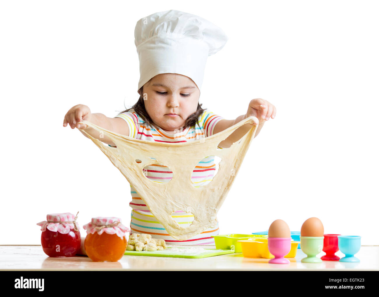 Bambina nel cappuccio della cuoca a giocare con la pasta Foto Stock