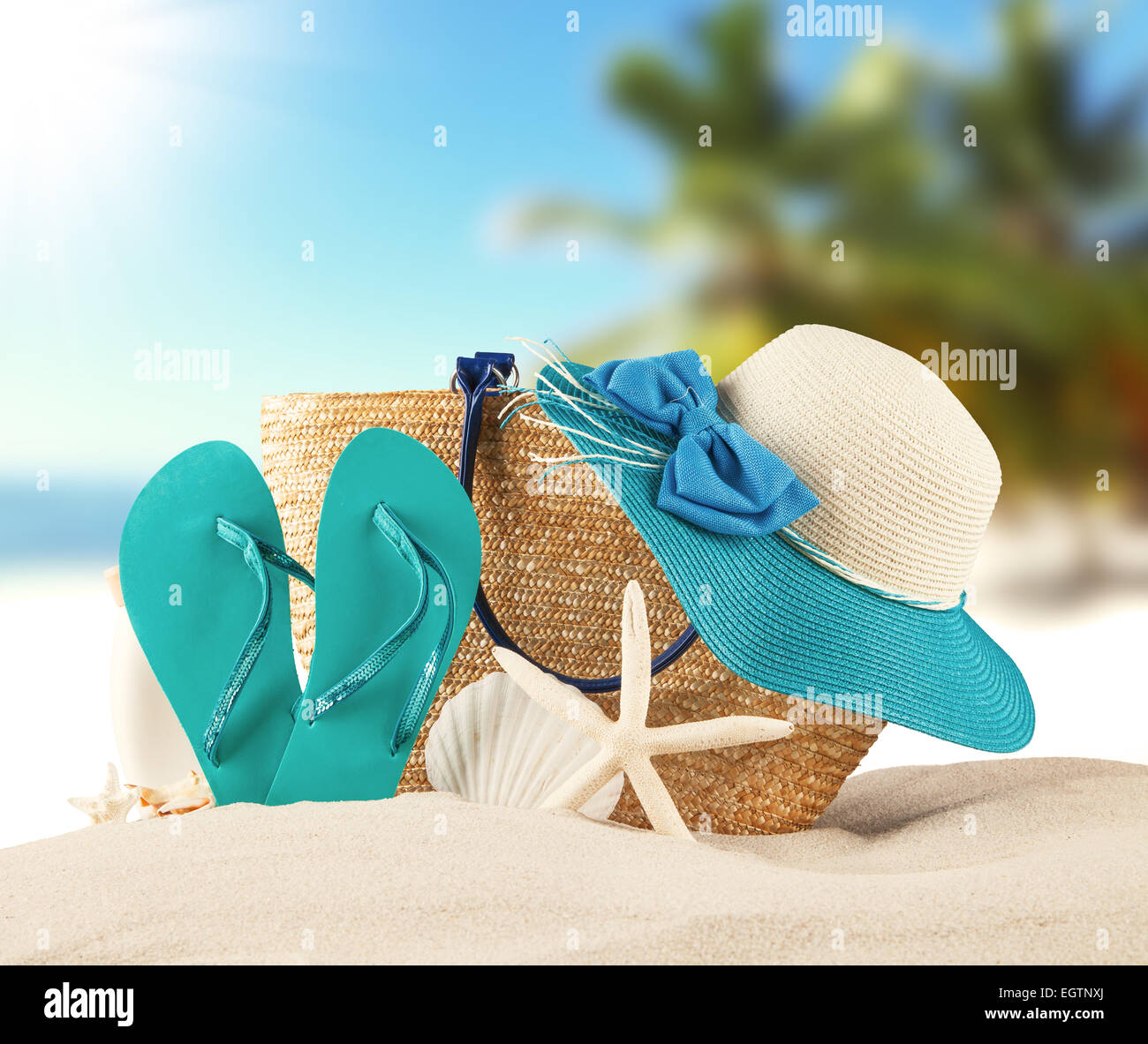 Concetto di estate con spiaggia sabbiosa, conchiglie e sandali blu Foto Stock