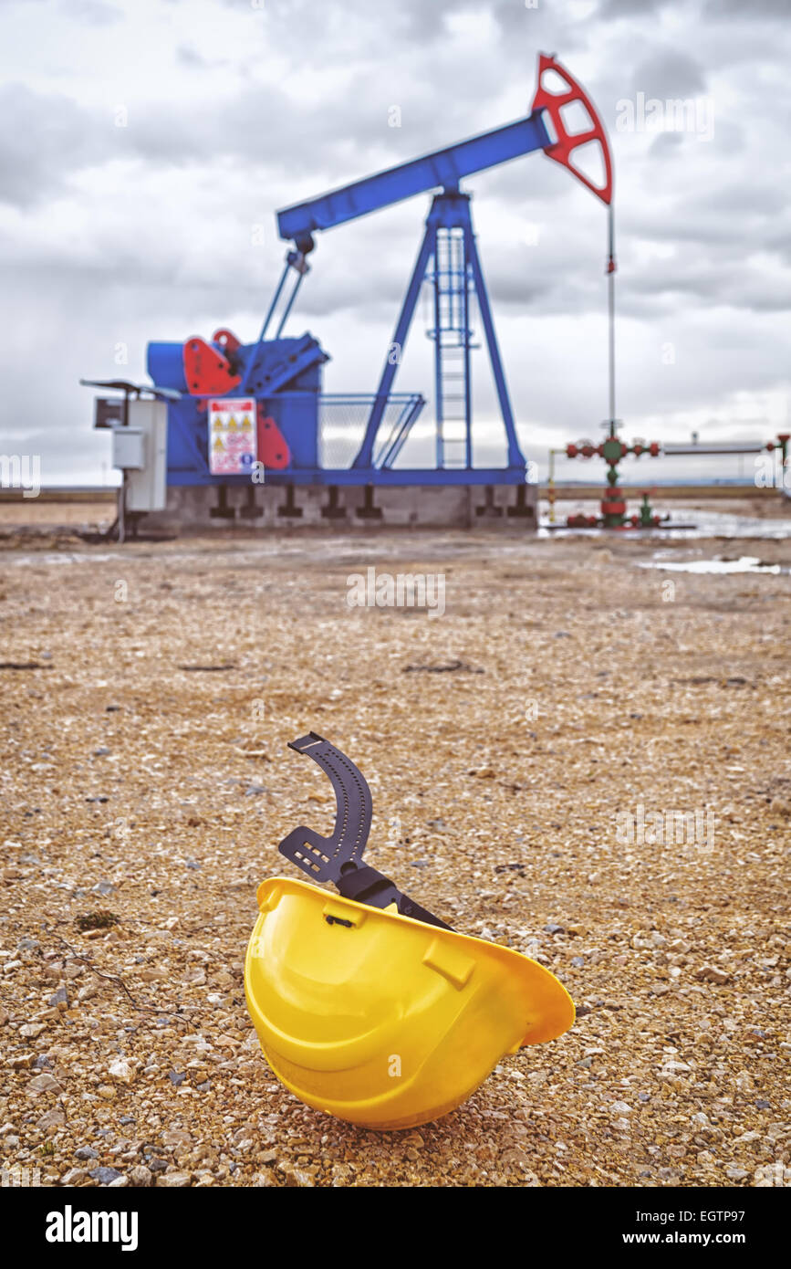 Casco industriale e Pumpjack pompa olio funzionante a gas naturale nel campo il pompaggio da pozzo petrolifero. Foto Stock