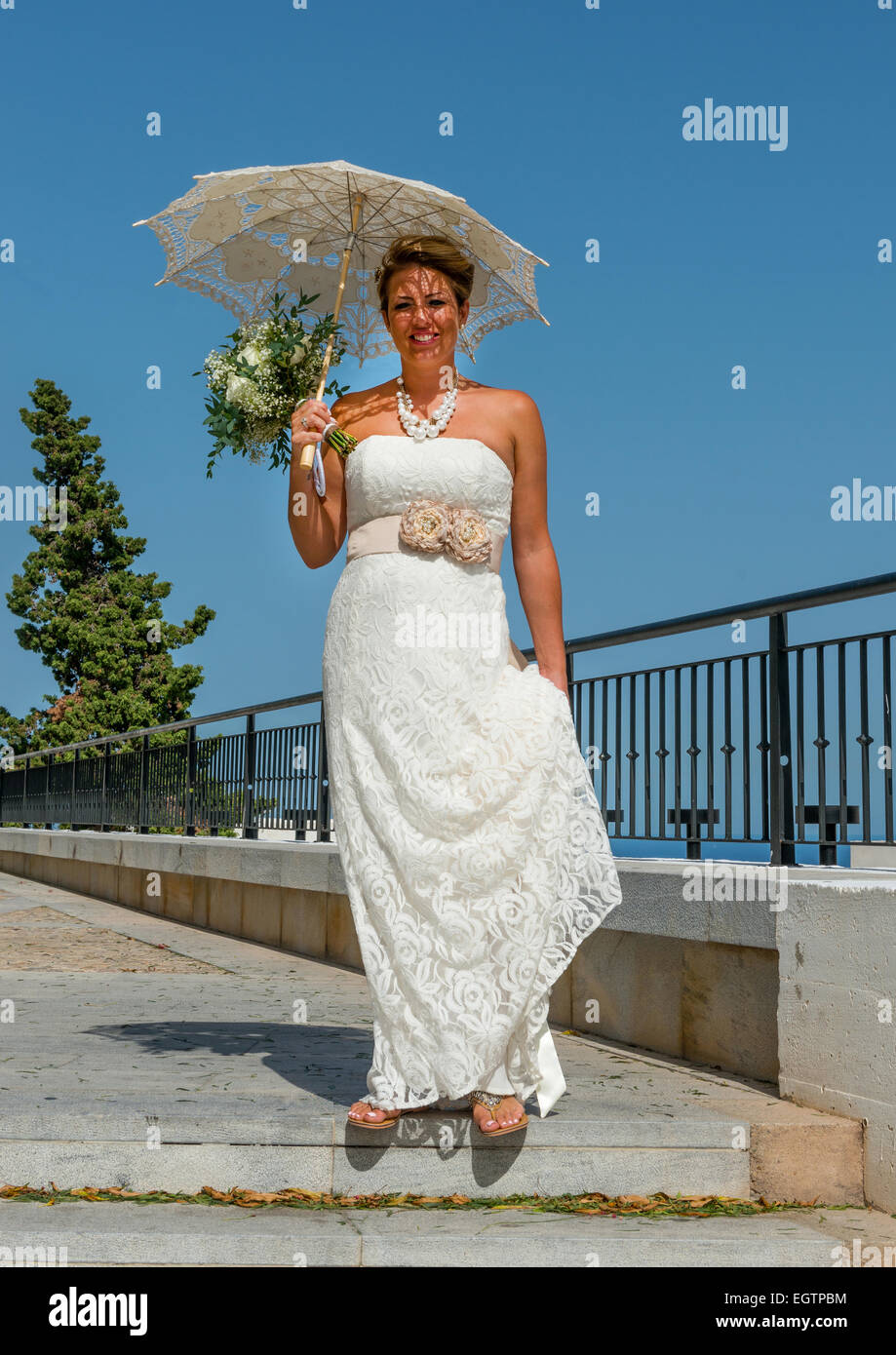 Sposa sul suo modo alla Chiesa, tenendo un ombrello bianco a Mojacar Andalusia, Spagna Foto Stock