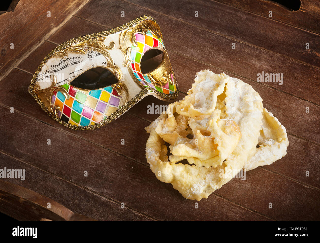 Tipica pasta fritta di feste di carnevale con maschera Veneziana. Questi dolci sono chiamati in diversi modi, chiacchiere, galani cenci Foto Stock
