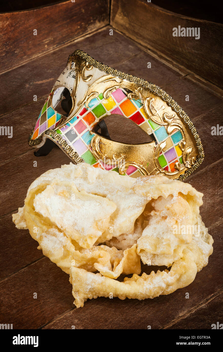 Tipica pasta fritta di feste di carnevale con maschera Veneziana. Questi dolci sono chiamati in diversi modi, chiacchiere, galani Foto Stock